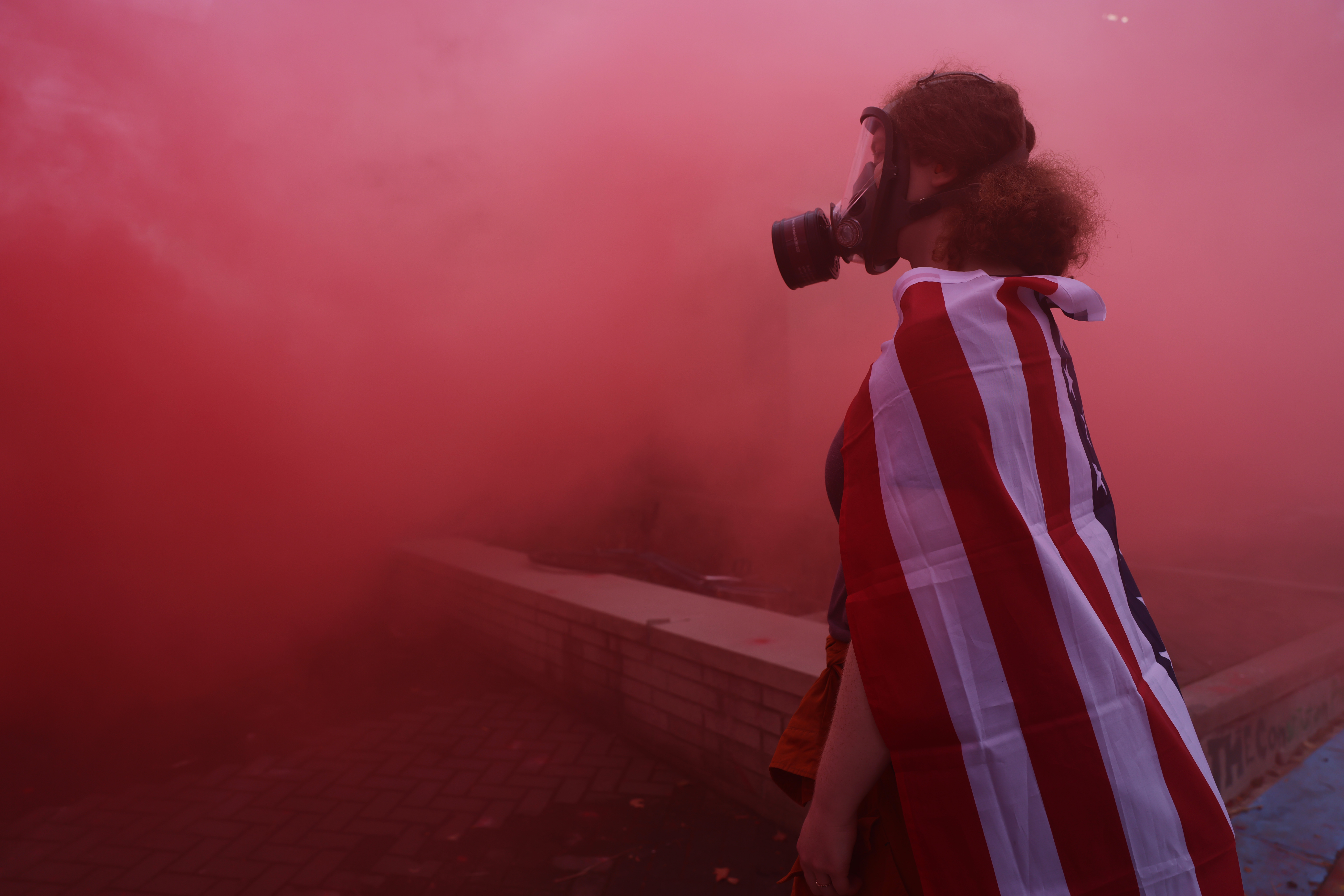 A protester stands in the haze from a smoke grenade outside of a downtown U.S. Immigration and Customs Enforcement (ICE) facility on October 04, 2025 in Portland, Oregon. The facility has become a focal point of nightly protests against the Trump administration and his announcement that he will be sending National Guard troops into Portland. A federal judge is currently hearing Oregon’s case against sending troops into the city, and a decision is expected on Saturday.  (Photo by Spencer Platt/Getty Images)