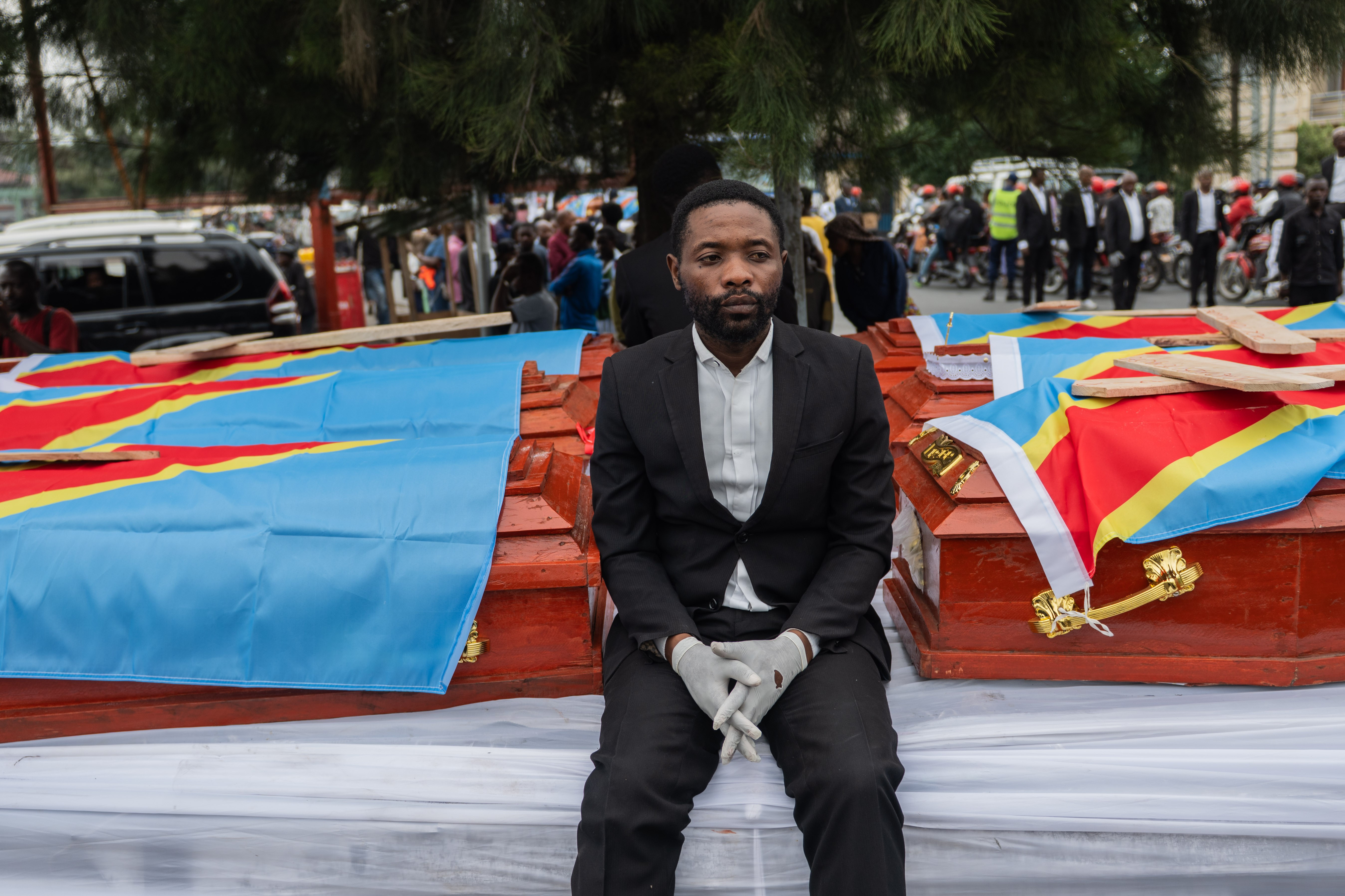 Pallbearers sit next to coffins loaded on tracks during a collective memorial service organized by the Alliance Fleuve Congo (AFC) and the M23 armed group for the victims of an attack in early January, in Masisi, North Kivu, Democratic Republic of the Congo, 08 January 2026. The burial follows deadly clashes that broke out on 02 January between the Rwandan-backed M23 armed group and the Armed Forces of the Democratic Republic of the Congo (FARDC).  EPA/MOISE KASEREKA