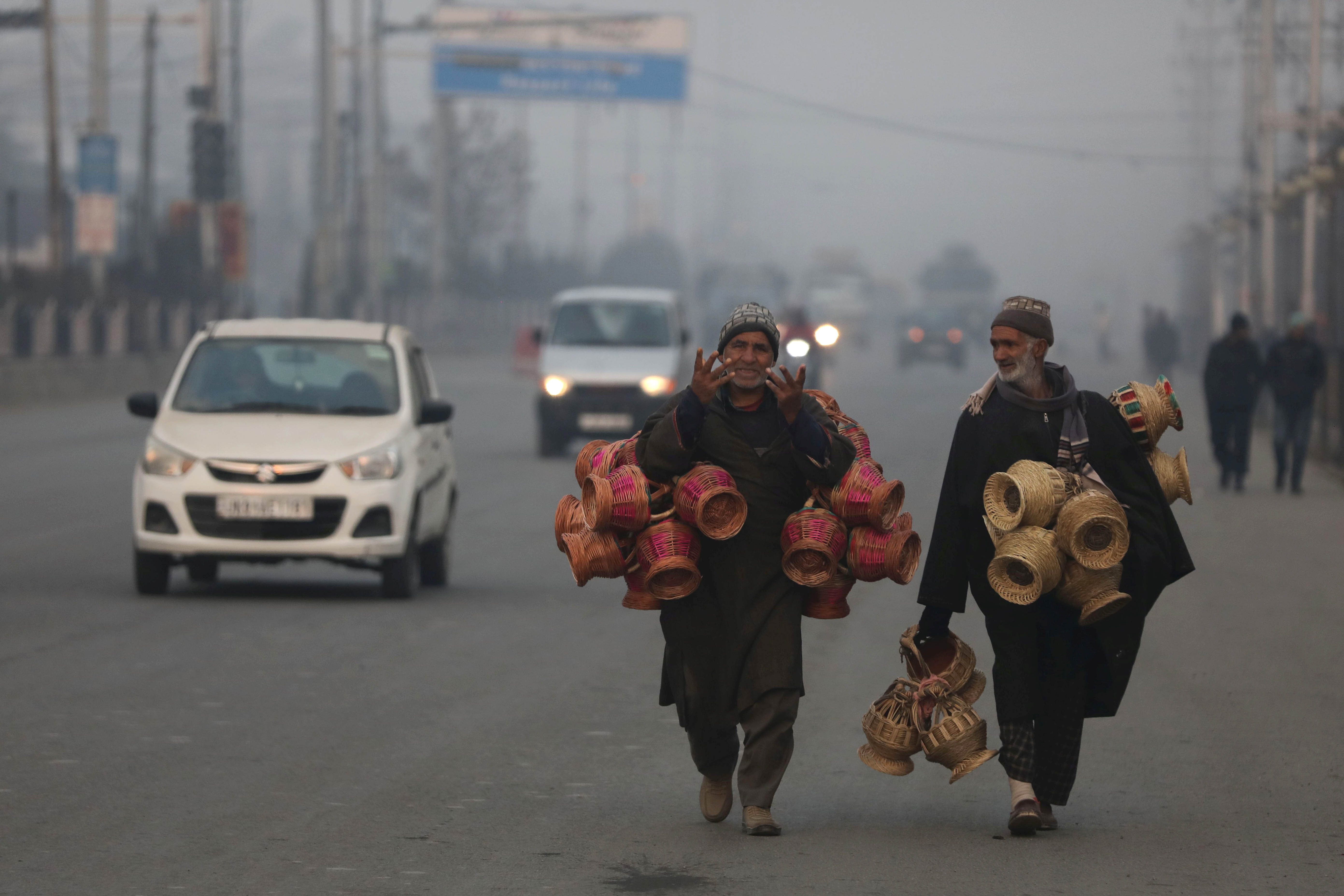 Fire pot (traditional Kangri) sellers walk amid fog on a cold morning in Srinagar, the summer capital of Indian Kashmir, 17 January 2026. Kashmir remains in the grip of Chillai Kalan, the harshest phase of winter, marked by cold and dry weather.  EPA/FAROOQ KHAN