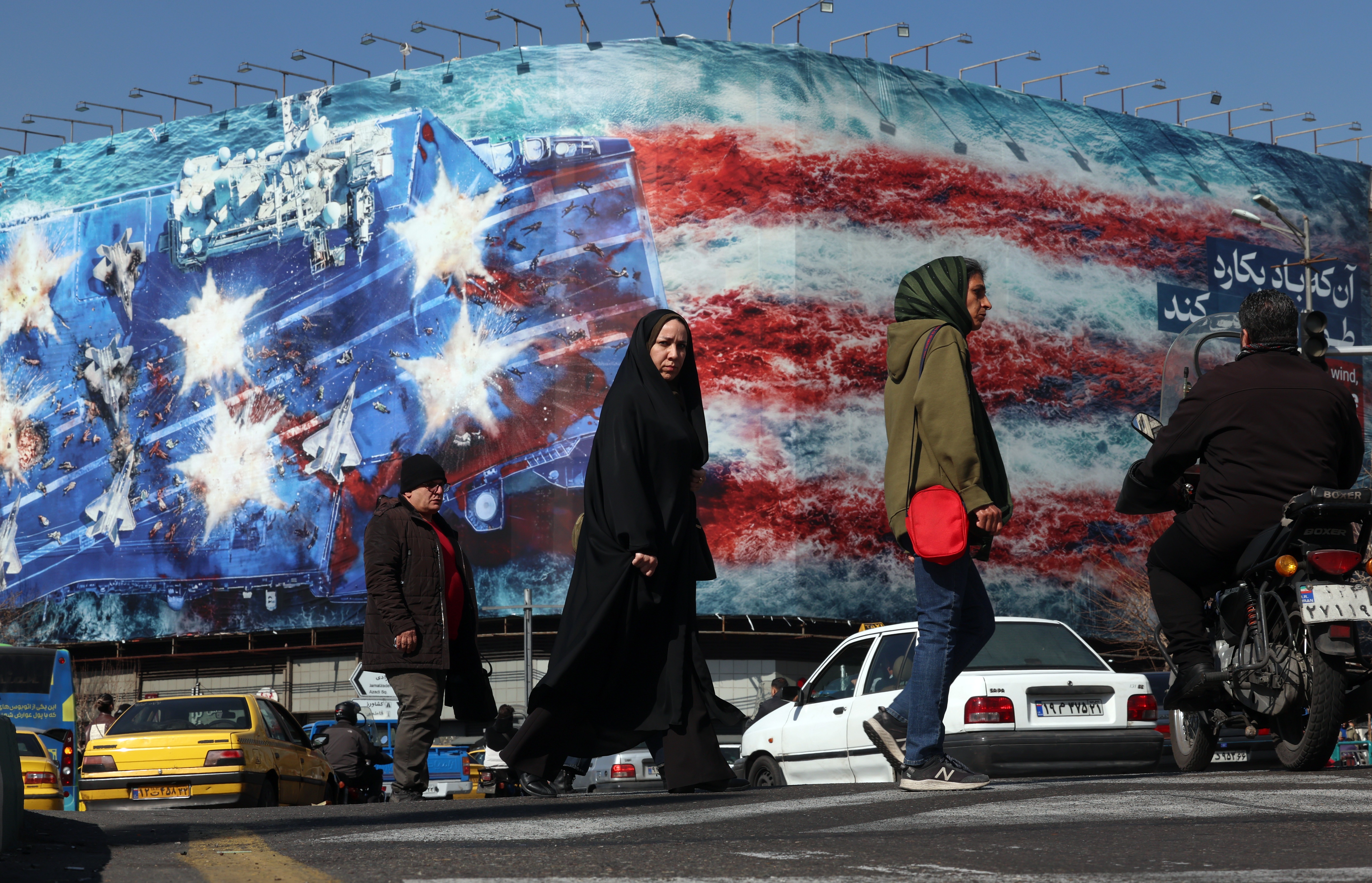 Iranians walk past an anti-US billboard at Enqelab Square in Tehran, Iran, 16 February 2026. Iran and the US will hold the second round of talks on 17 February 2026 in Geneva, Switzerland.  EPA/ABEDIN TAHERKENAREH
