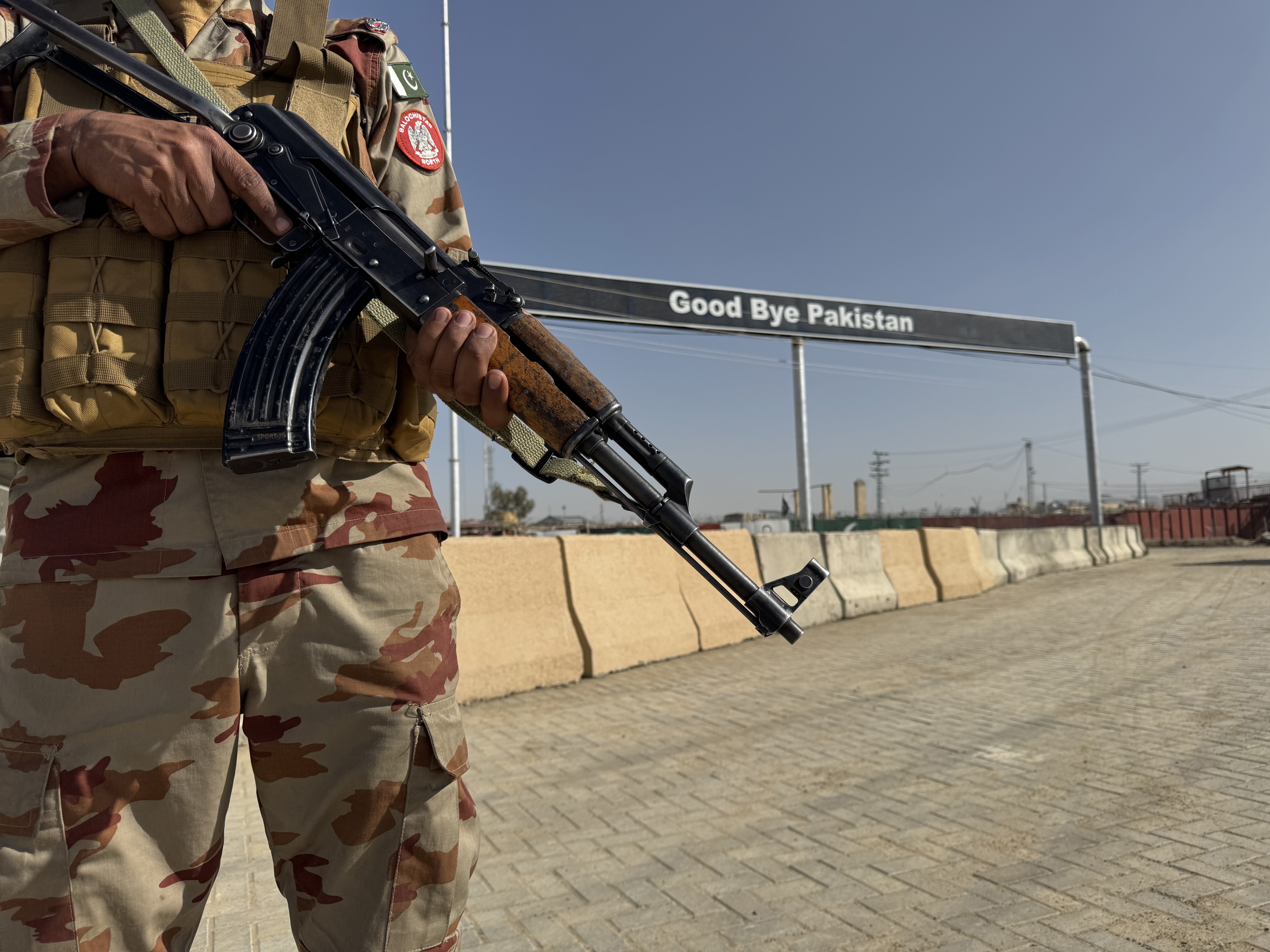 A Pakistani paramilitary soldier stands guard as Afghans arrested for illegally crossing into Iran through the Pak-Iran border line up to be sent back to Afghanistan at the Pak-Afghan border in Chaman, 24 February 2026. Turbat police arrested at least 50 Afghan nationals during a search operation for allegedly attempting to travel illegally to Iran. Authorities said the individuals had been residing in Pakistan and were planning to cross the border unlawfully. They were deported to Afghanistan via the Chaman border crossing. Police added that the crackdown on undocumented migrants has pushed some Afghans to try moving to Iran. The group included women and children.  EPA/AKHTAR GULFAM