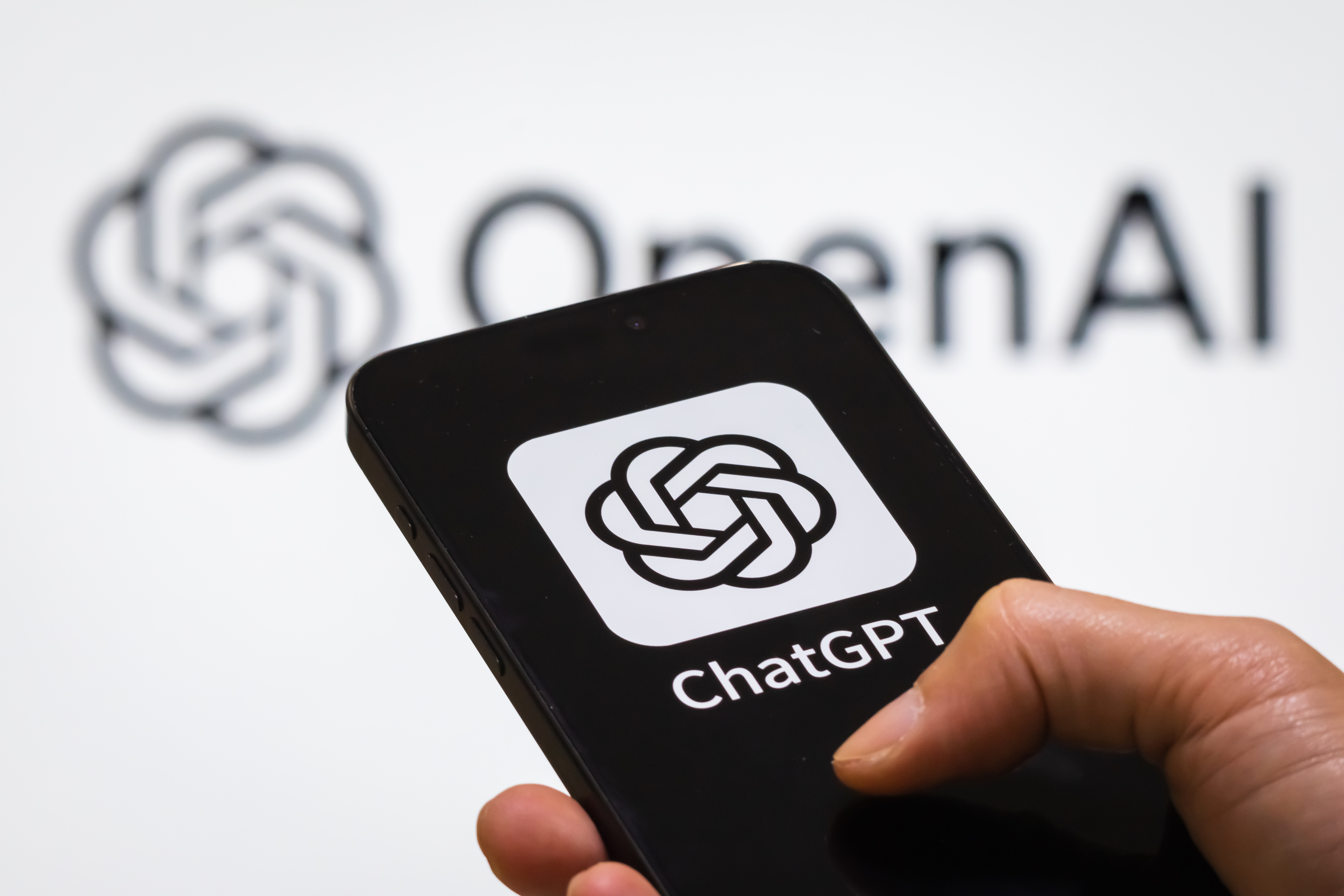 A person holds a smartphone displaying the ChatGPT logo in front of the OpenAI logo. (Photo: Cheng Xin/Getty Images)