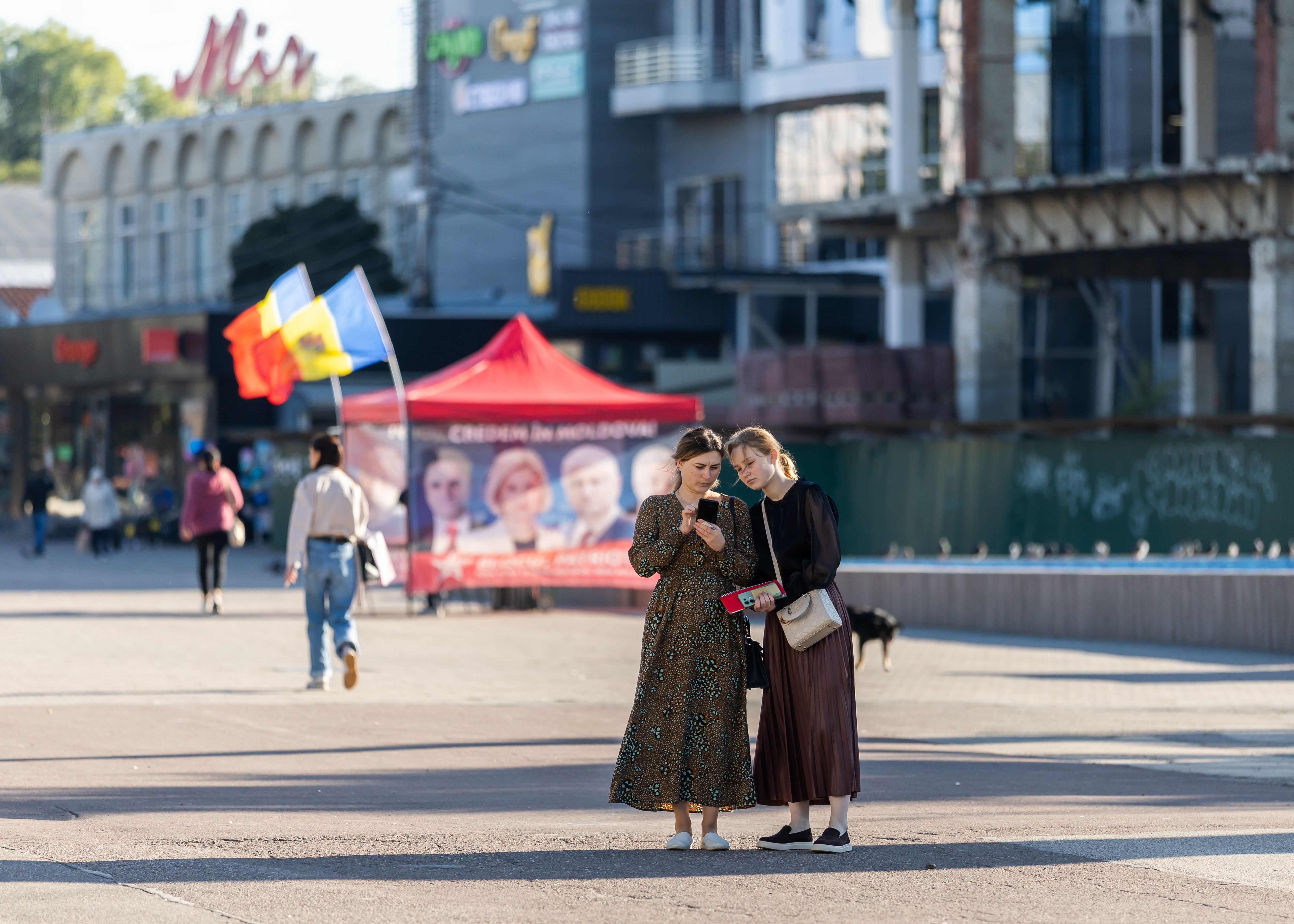 Two young women look at a mobile phone as they stand near an electoral campaign tent in Balti, Moldova, 23 September 2025. Moldova's parliamentary elections are scheduled for 28 September 2025.  EPA/EPA/DUMITRU DORU