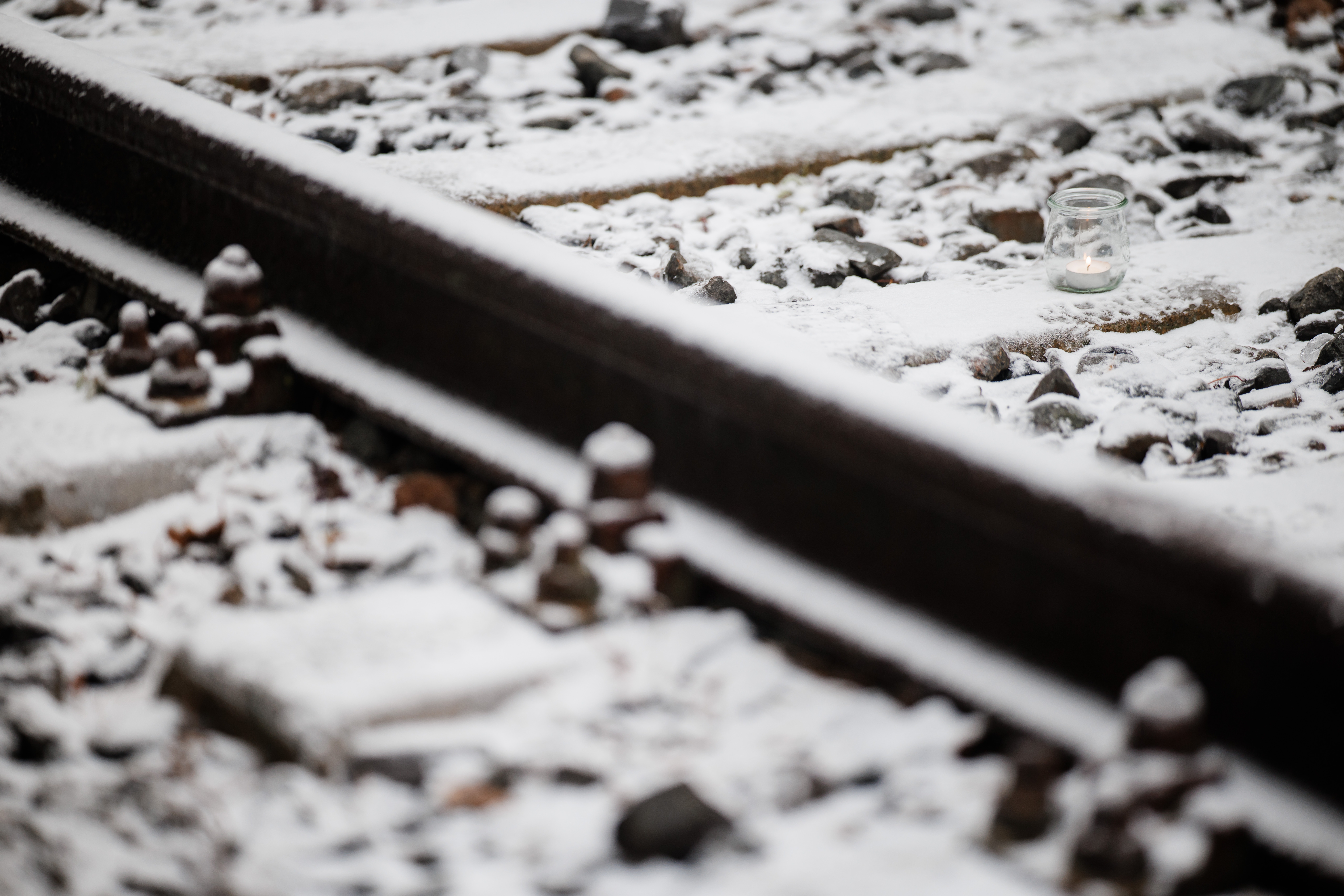 A candle in a glass stands on snow-covered train tracks during a commemoration event for the victims of National Socialism at the Moabit Freight Station Memorial Site (in German: Gedenkort Gueterbahnhof Moabit) in Berlin, Germany, 27 January 2026. International Holocaust Remembrance Day is observed annually on 27 January.  EPA/CLEMENS BILAN