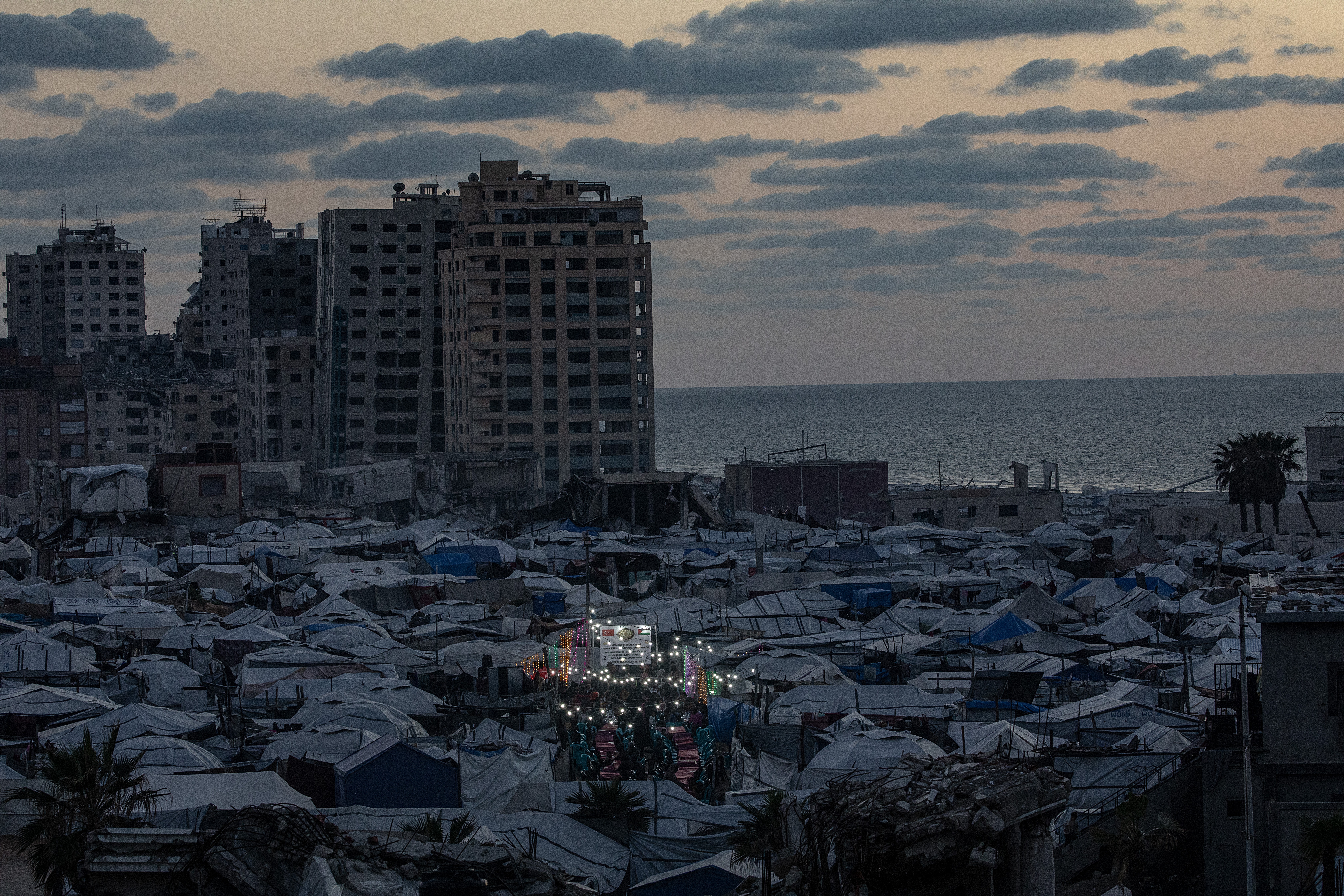 Displaced Palestinian people gather between makeshift tents to break their fast with an iftar meal together during the holy fasting month of Ramadan in the west of Gaza, 06 March 2026. Muslims around the world celebrate Ramadan by praying during the nighttime and abstaining from eating, drinking, and sexual acts during the period between sunrise and sunset.  EPA/MOHAMMED SABER