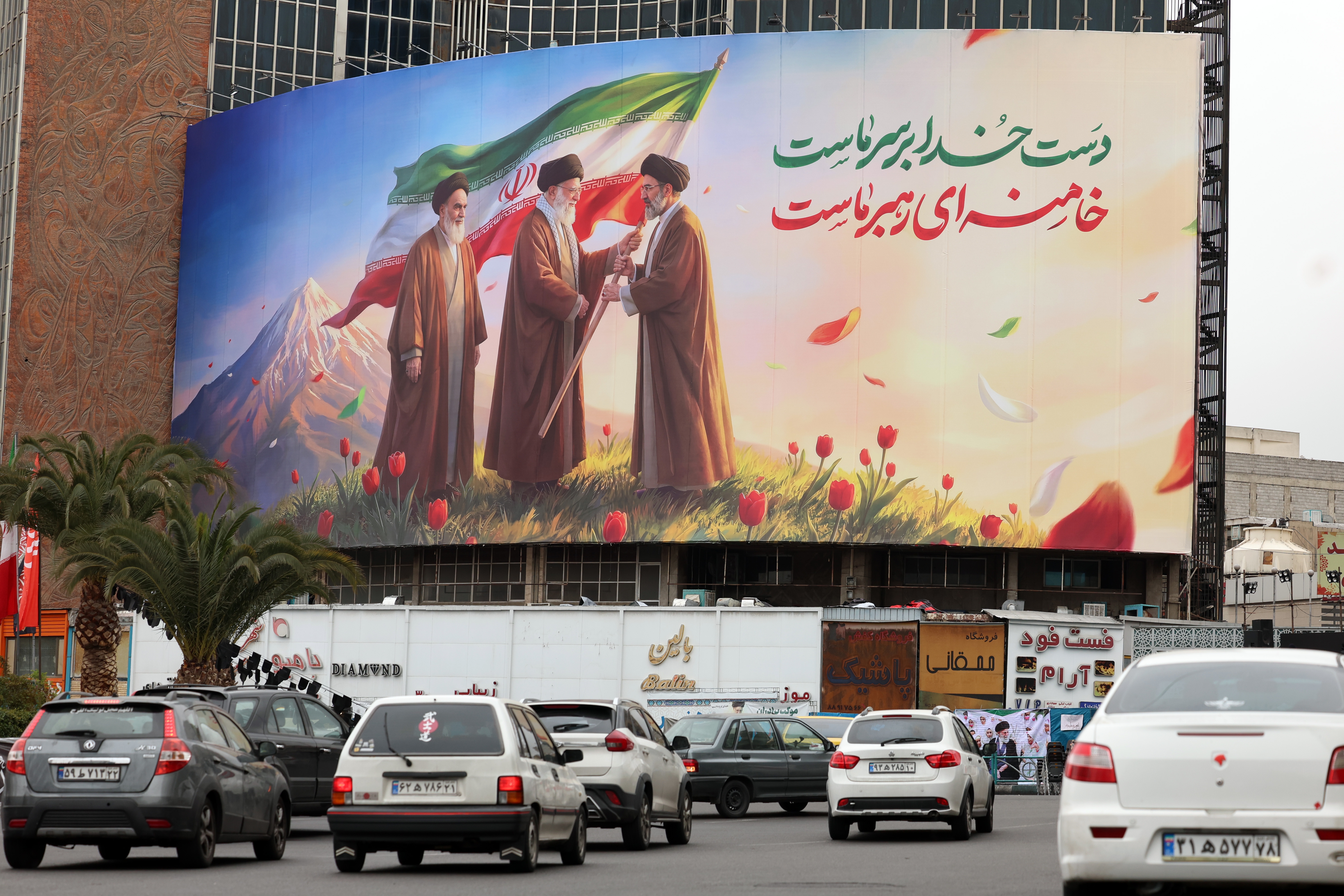 People drive past a huge billboard showing the late Iranian supreme leaders Ayatollah?Ruhollah Khomeini?(L), Ayatollah?Ali?Khamenei?(C), and the new Iranian supreme leader Ayatollah?Mojtaba?Khamenei?(R) at Valiasr Square in Tehran, Iran, 10 March?2026. The late Supreme Leader Ayatollah Ali Khamenei was killed during a joint US-Israel military operation across Iran in the early hours of 28 February 2026.  EPA/ABEDIN TAHERKENAREH