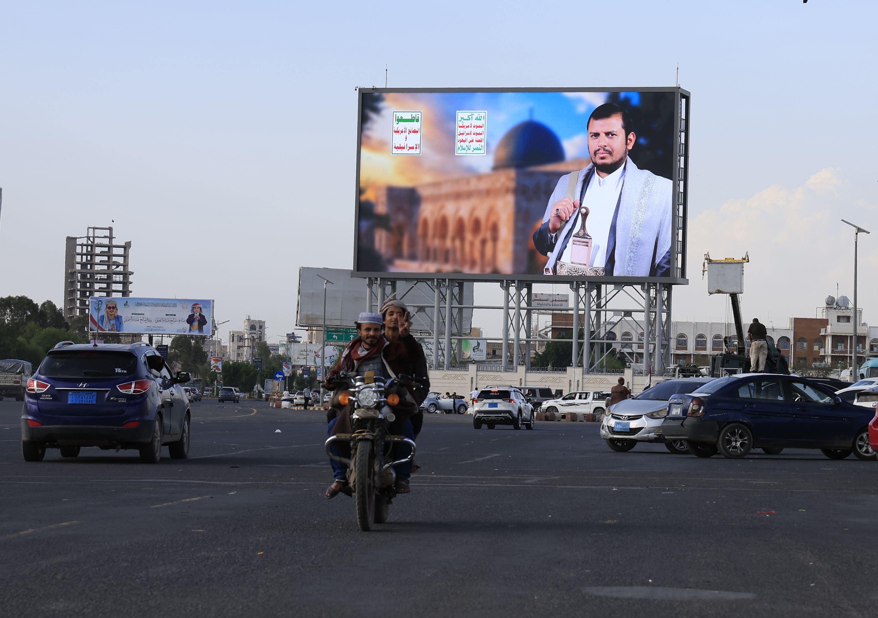A motorcycle and vehicles drive past a digital billboard featuring Houthi leader Abdul-Malik al-Houthi in Sana'a, Yemen, 09 April 2026. Yemen?s Houthi leader Abdul-Malik al-Houthi, in a televised address, described the US?Iran ceasefire as a ?big victory? for Tehran, asserting that the closure of the Strait of Hormuz functioned as a major pressure tactic against the United States and Israel.  EPA/YAHYA ARHAB