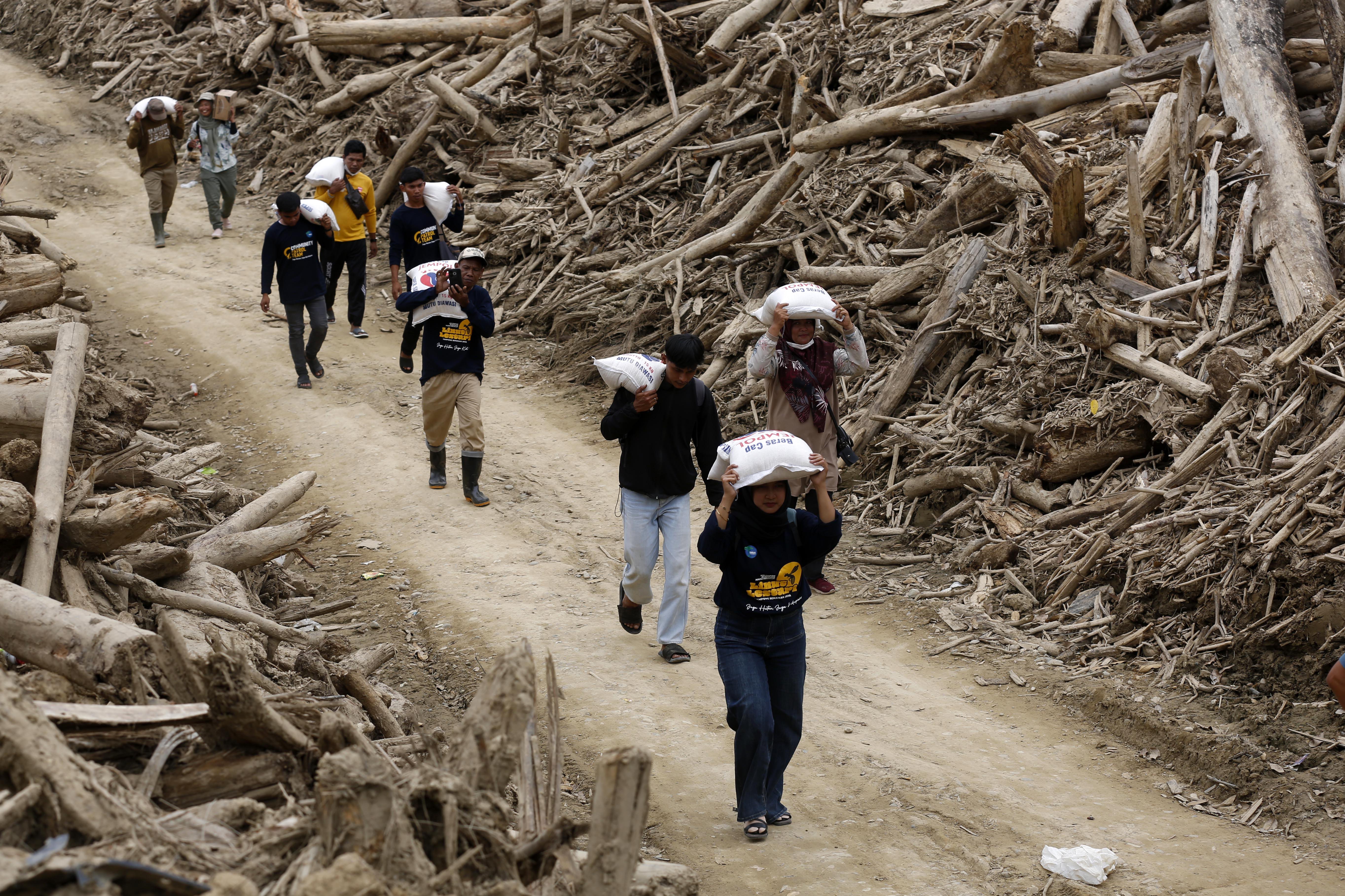 Volunteers from local NGO Yayasan Hutan, Alam dan Lingkungan Aceh (HaKa) distribute food aid at a flood-affected area at Sekumur Village, Aceh Tamiang, Aceh, Indonesia, 06 February 2026. The Indonesian government stated that the post-disaster recovery process remains slow due to several obstacles, such as damaged bridge infrastructure and difficulties in determining relocation sites for flood victims.  EPA/HOTLI SIMANJUNTAK