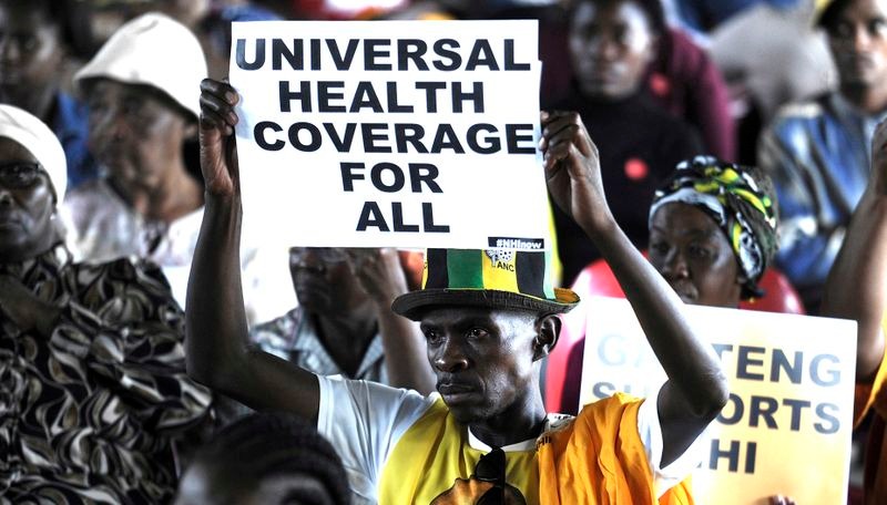 A protester holds up a poster saying "universal health coverage for all"