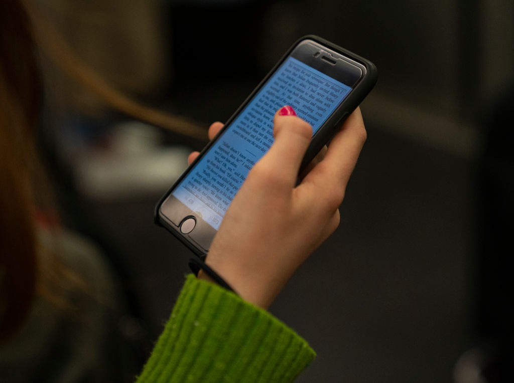 A woman reads a book on her iPhone. (Photo: Robert Nickelsberg/Getty Images)