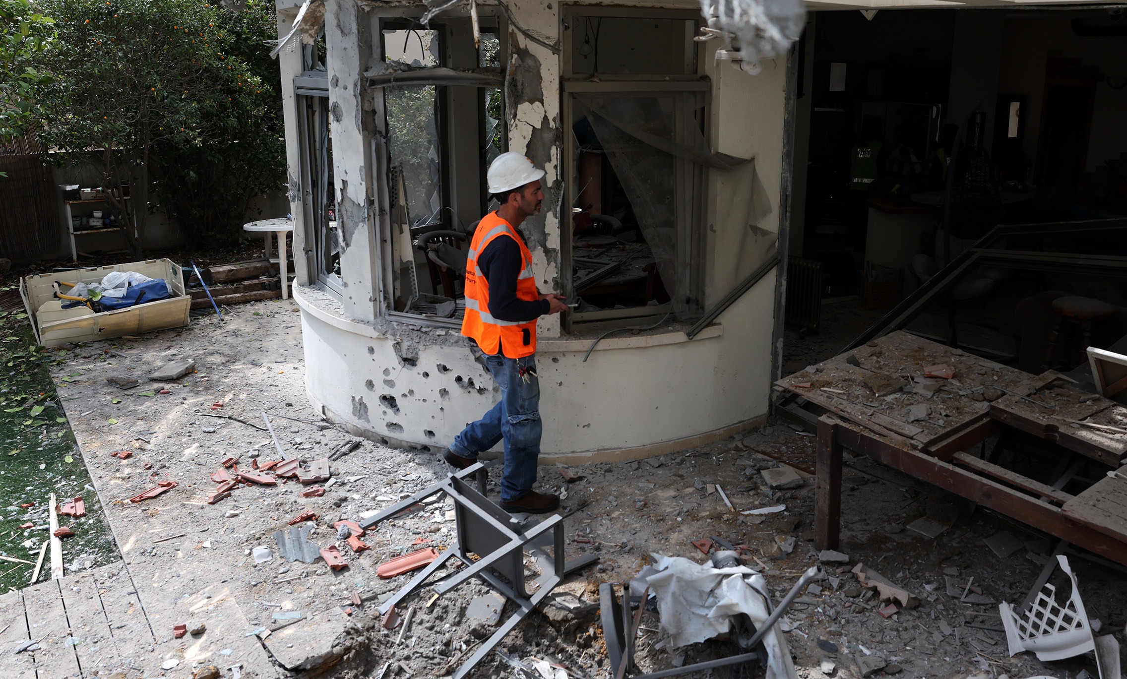 An electricity company employee inspects a damaged building at the site of a reported Iranian missile strike in Shoham, central Israel, on 16 March. (Photo: Abir Sultan / EPA)