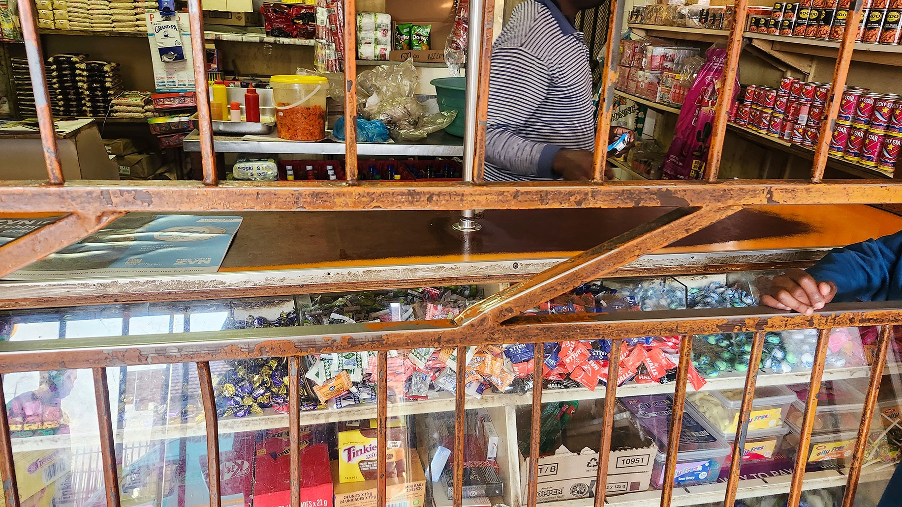 A young girl waits for her order inside a spaza shop in Naledi, Soweto. (Photo: Naomi Campbell)