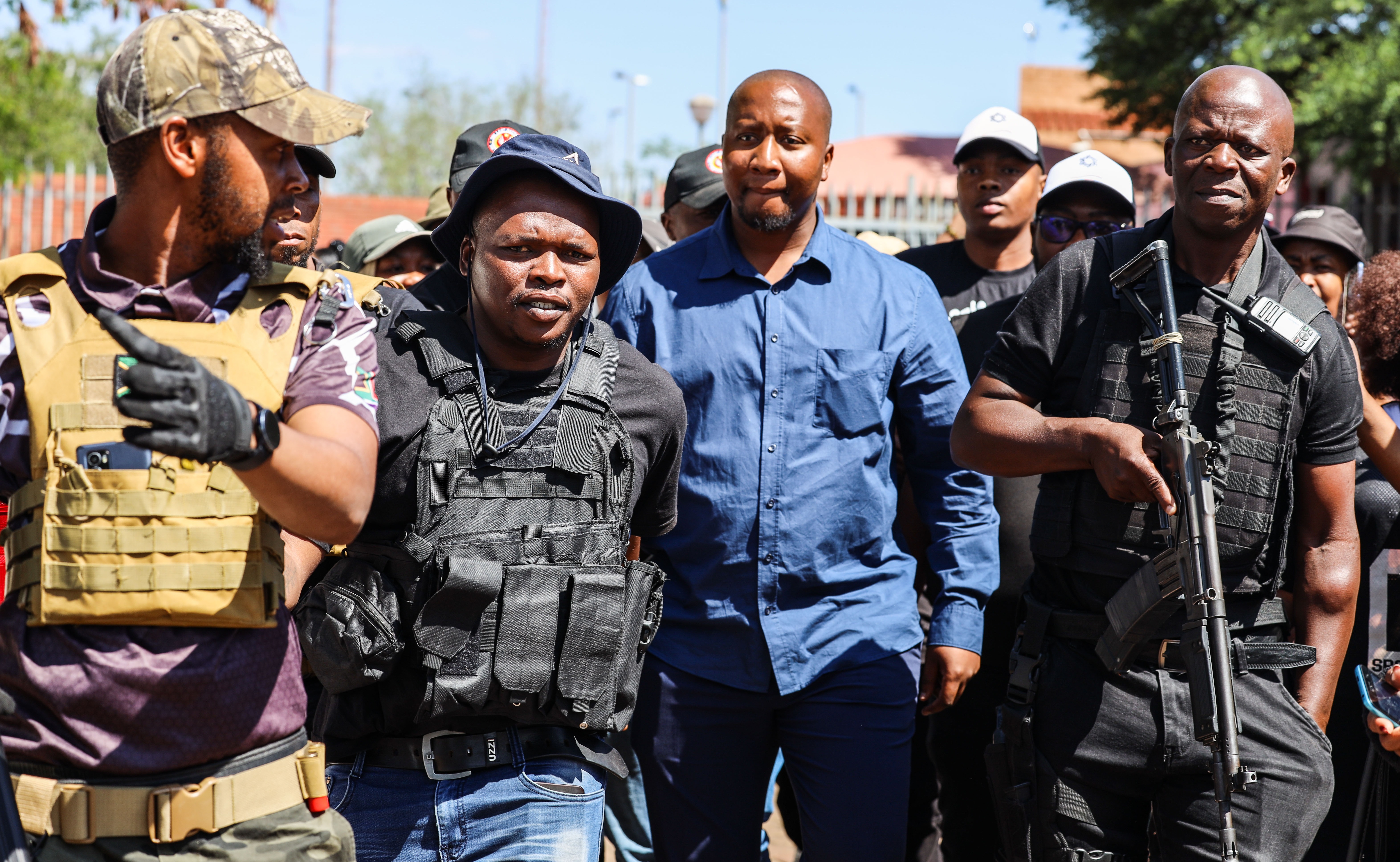 Xolani Khumalo, in blue, flanked by members of his security detail, arriving at Palm Ridge Magistrates’ Court last month on charges related to a December 2025 drug-bust operation. (Photo: OJ Koloti / Gallo Images)