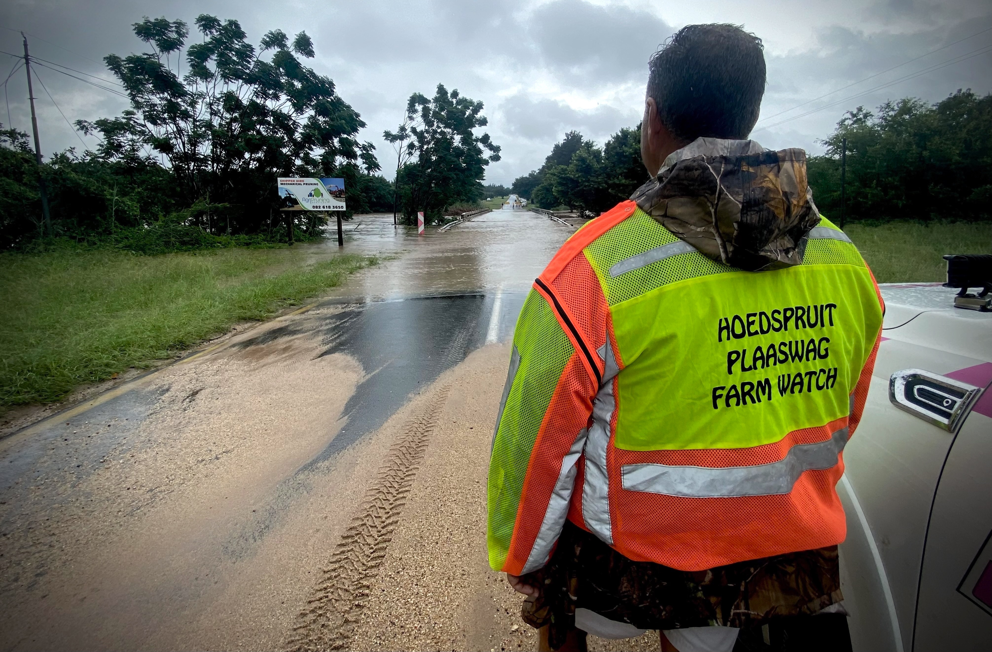 A security member of Hoedspruit Farm Watch observes the Zandspruit River overflowing onto the Zandspruit Bridge on the R527 leading out of Hoedspruit, Limpopo, on 13 January. (Photo: Tiara Walters)