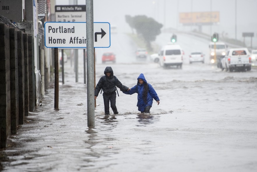 Two Portlands Primary School learners wade through the flooded Westpoort Road on their way to school in Mitchells Plain on Monday morning. (Photo: David Harrison)