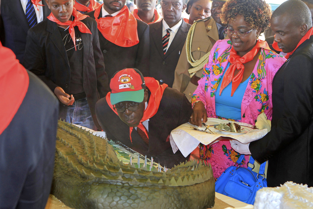 Zimbabwe's President Mugabe blows out candles on a cake during his 88th birthday rally in Mutare