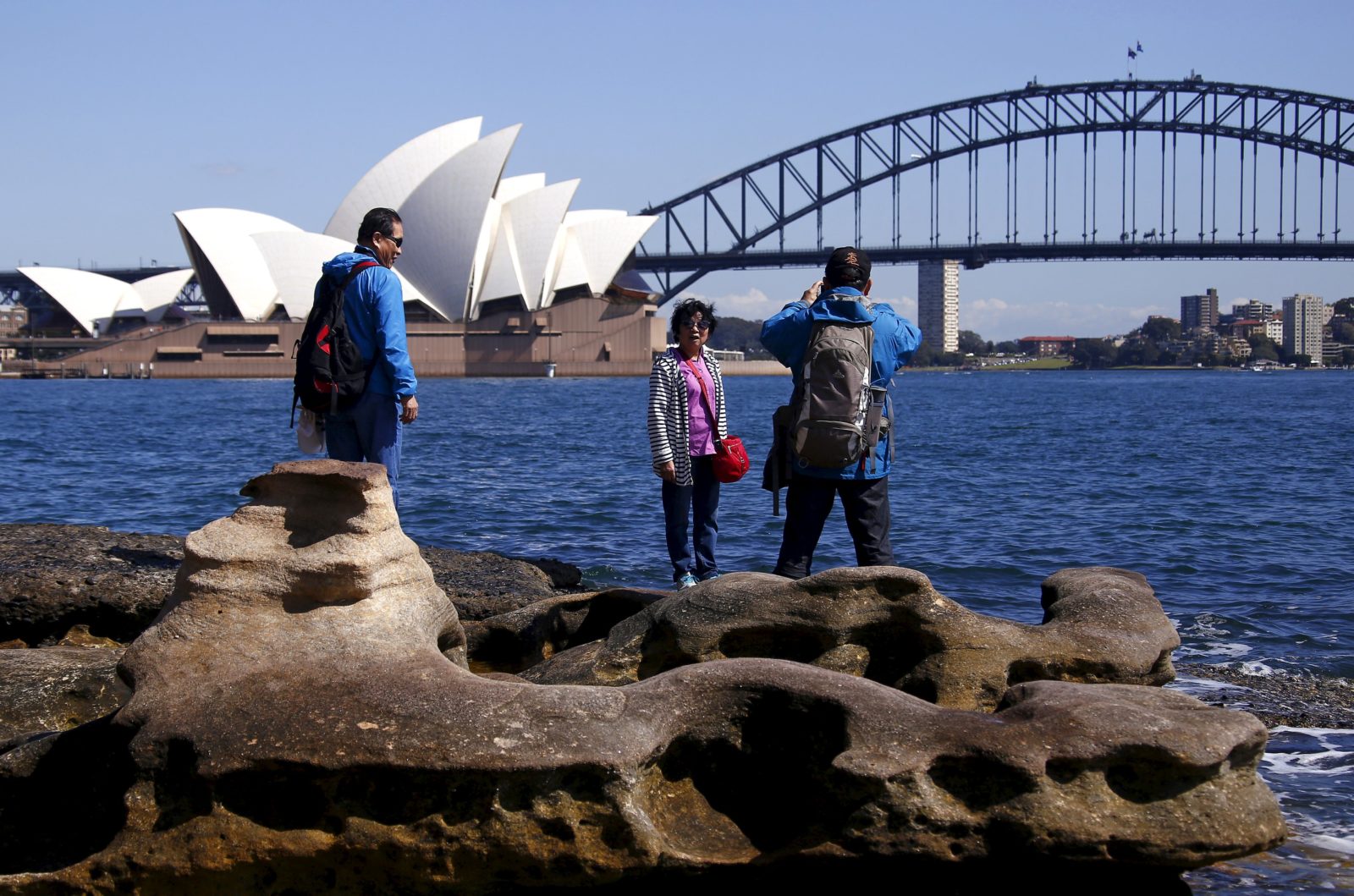 Chinese tourists take pictures of each other as they pose in front of the Sydney Opera House in Sydney, Australia