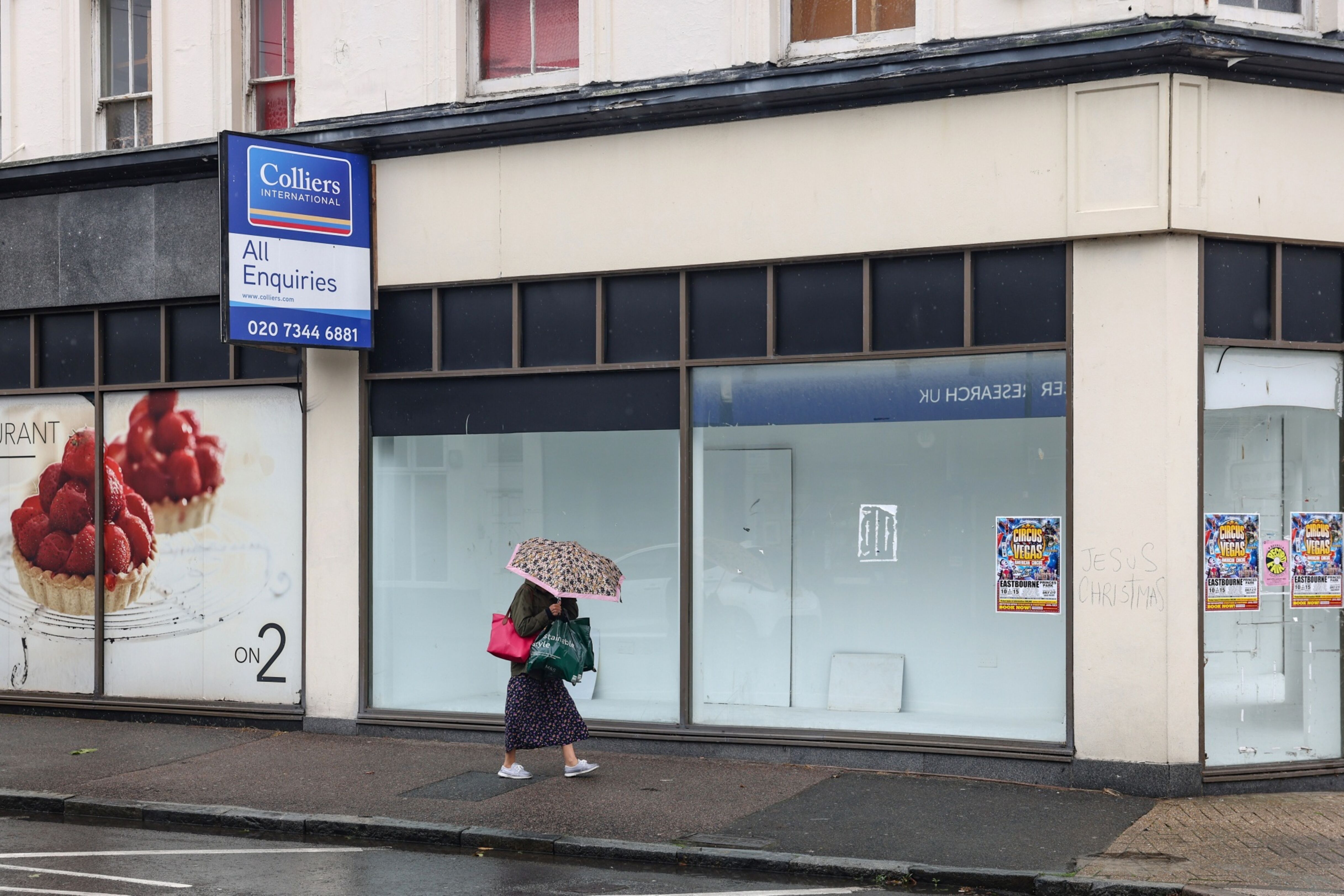 A woman passes a vacant retail unit on the high street in Eastbourne, UK