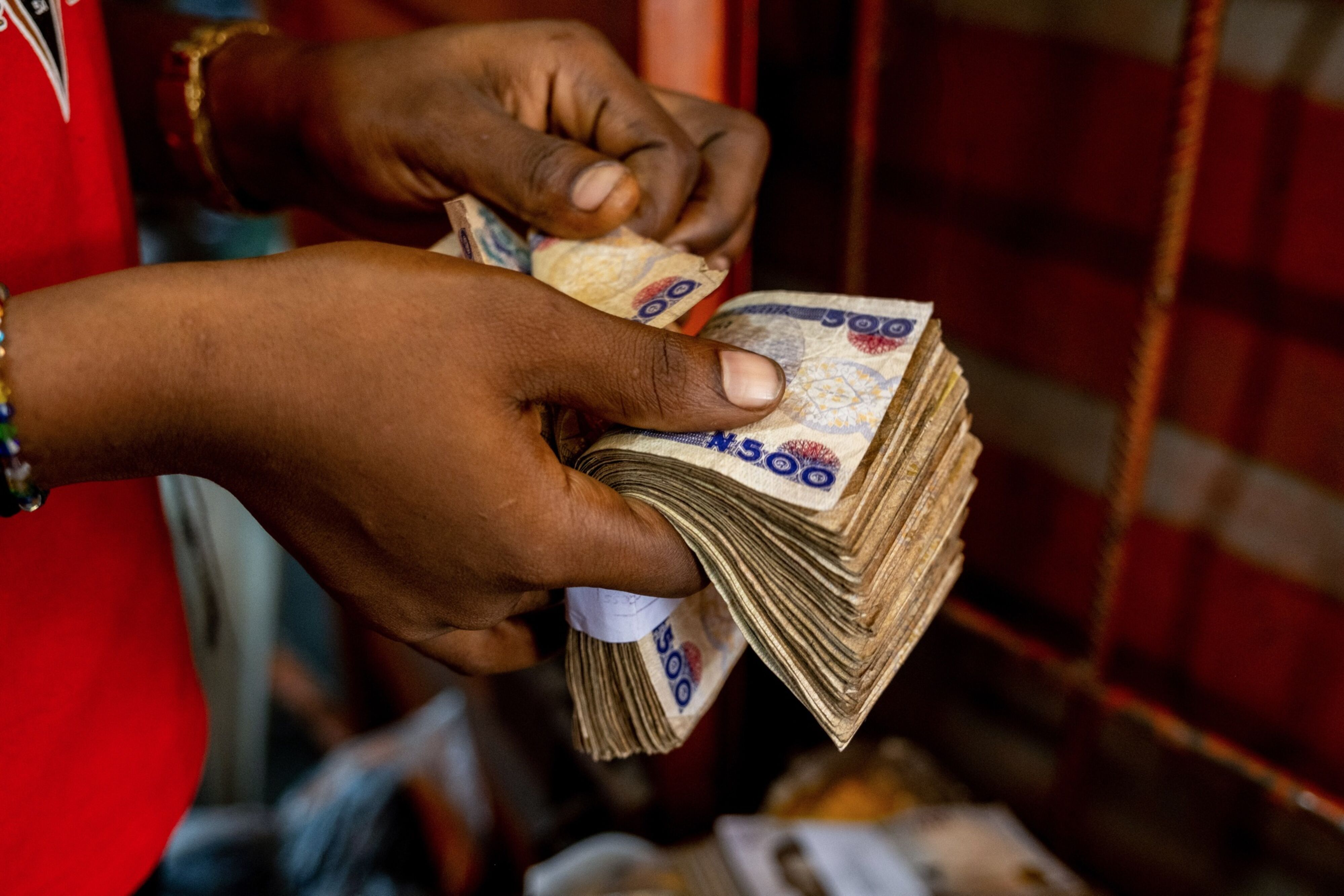 A customer counts Naira banknotes at a market in Lagos.
