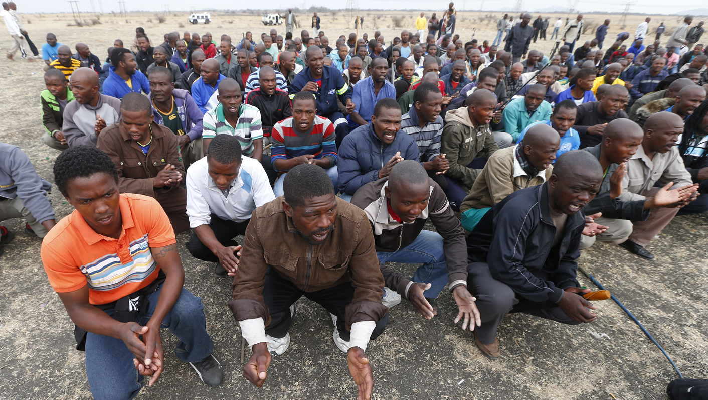 Mine workers gather while on strike near the scene of a shooting at Marikana