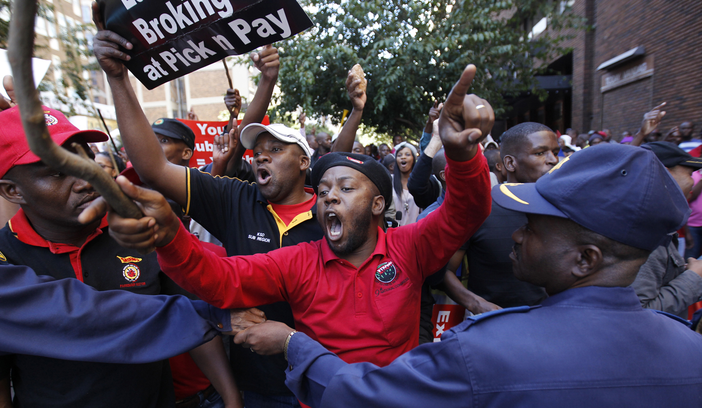 A policeman keeps watch as angry COSATU supporters chant slogans during a march by the Democratic Alliance in Johannesburg