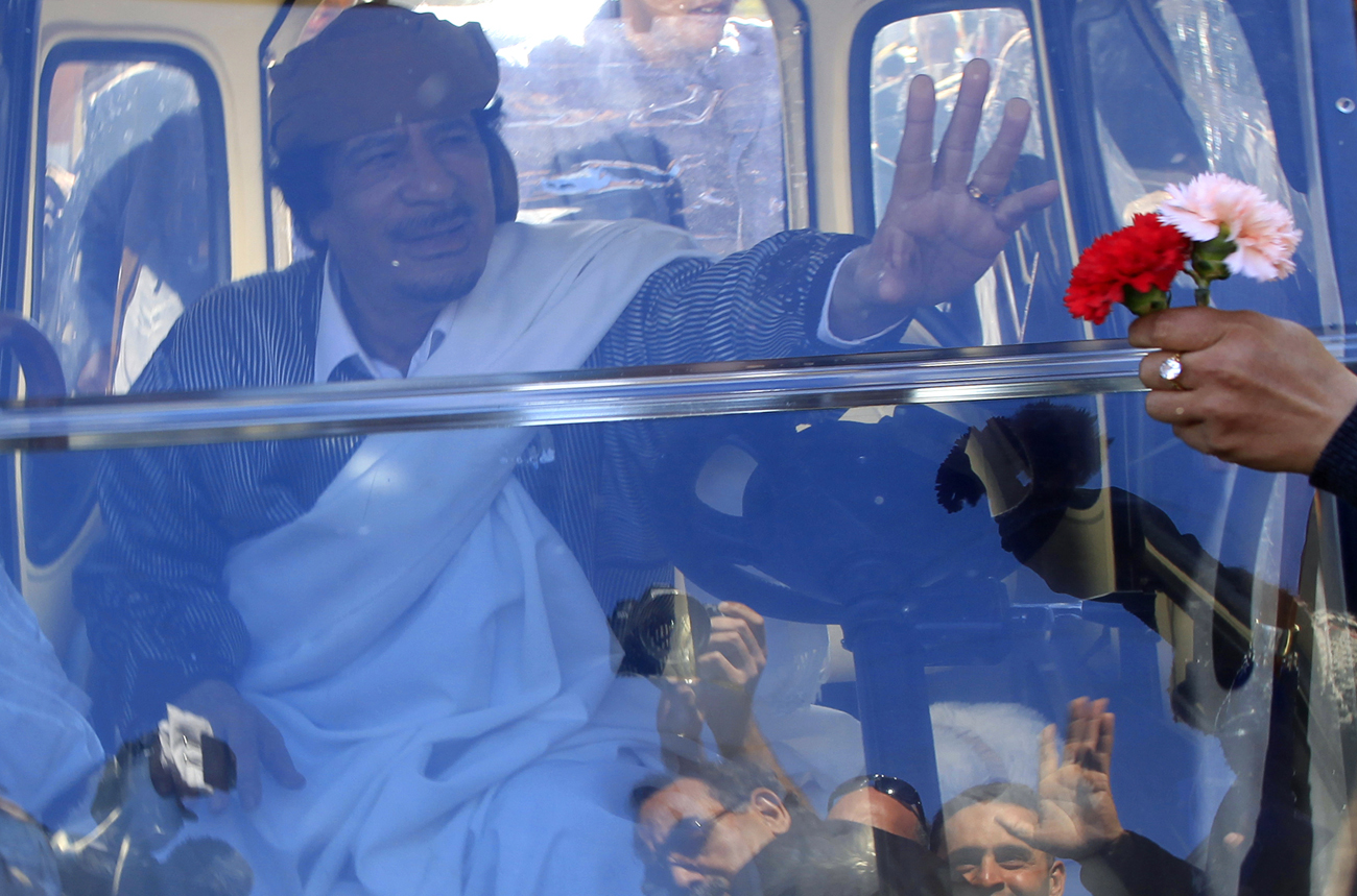 Libyan leader Gaddafi waves from his personal cart in Tripoli after making a speech