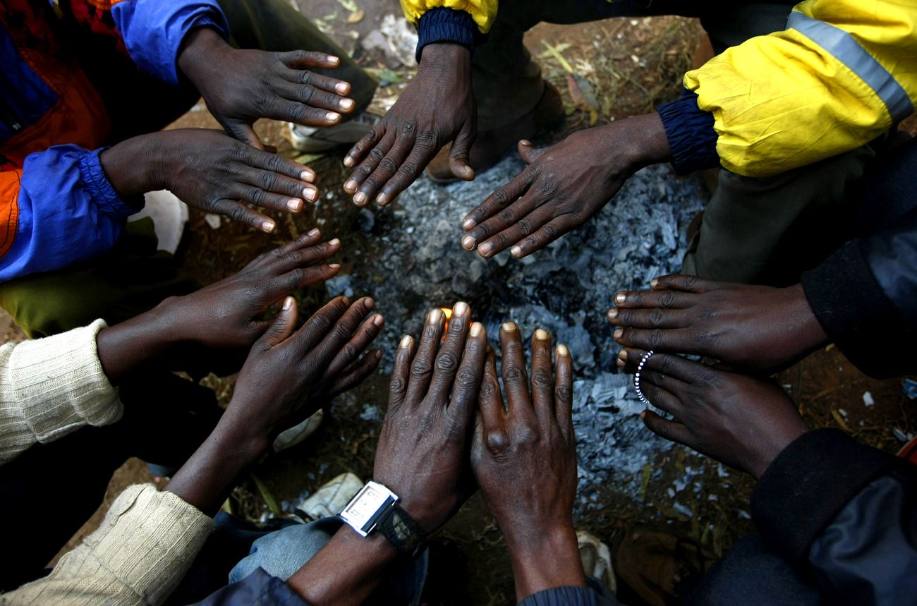 African immigrants, displaced by anti-foreigner violence in Johannesburg, warm their hands around a small fire outside the Jeppe police station in the city
