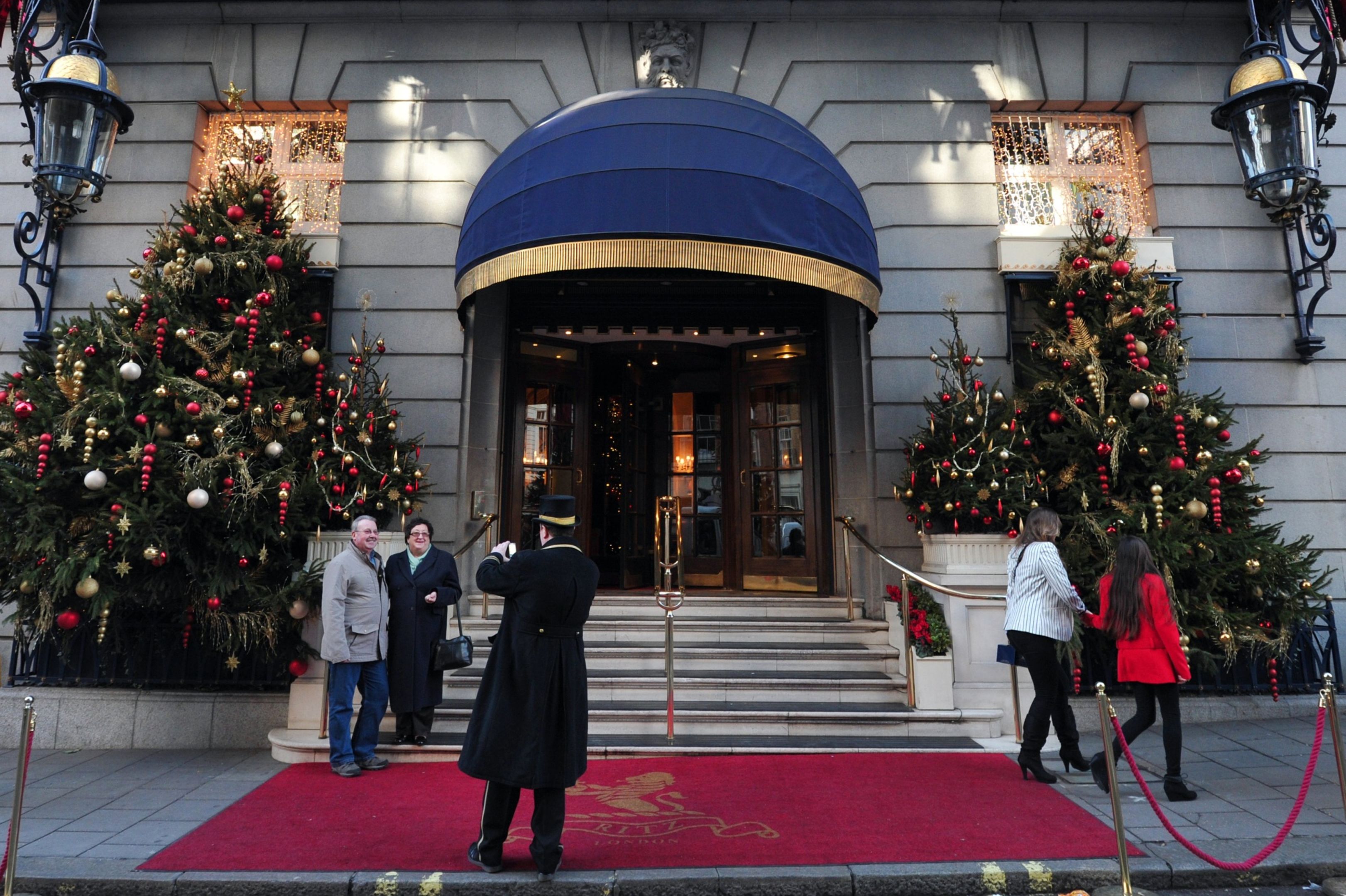 A doorman takes pictures of a couple outside the entrance to the Ritz hotel in central London Photographer: Carl Court/AFP/Getty Images