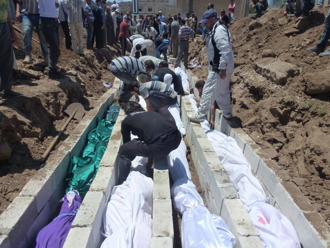 People gather at a mass burial for the victims purportedly killed during an artillery barrage from Syrian forces in Houla