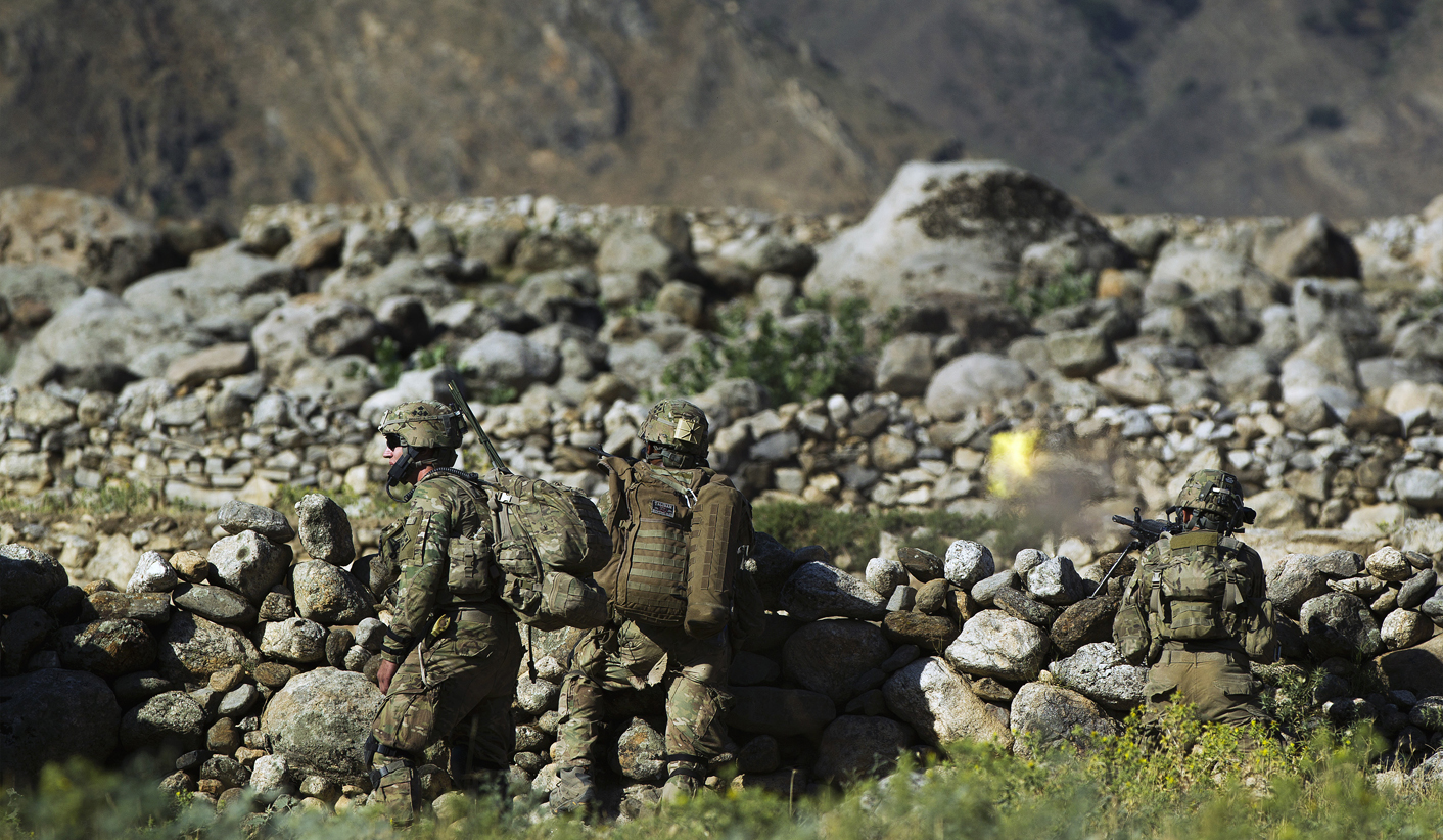 Soldiers take cover as Sergeant Austin Craig fires his weapon during an early morning patrol near the village of Qandaro in the Pech River Valley