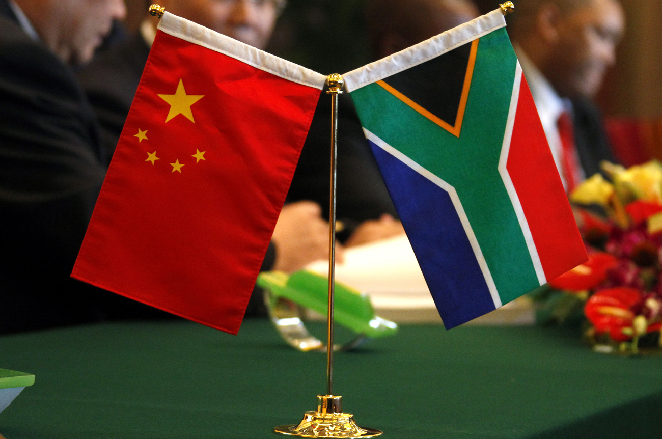 The South African and Chinese national flags sit atop a table as businessmen sign contracts during the China-South Africa Business Forum in Beijing