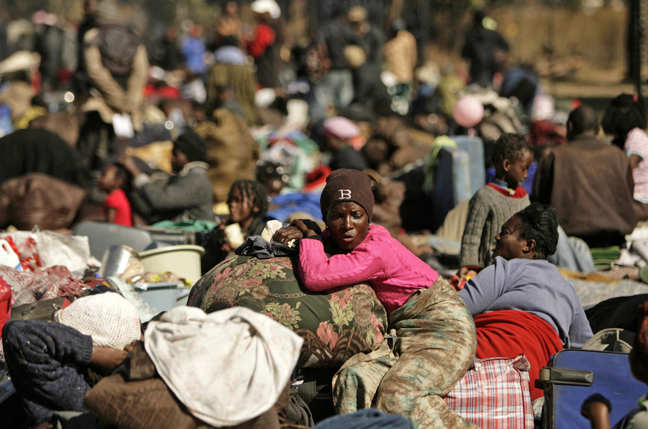 Refugees wait to be relocated by the police to a temporary shelter after camping for five days by a major road in Krugersdorp