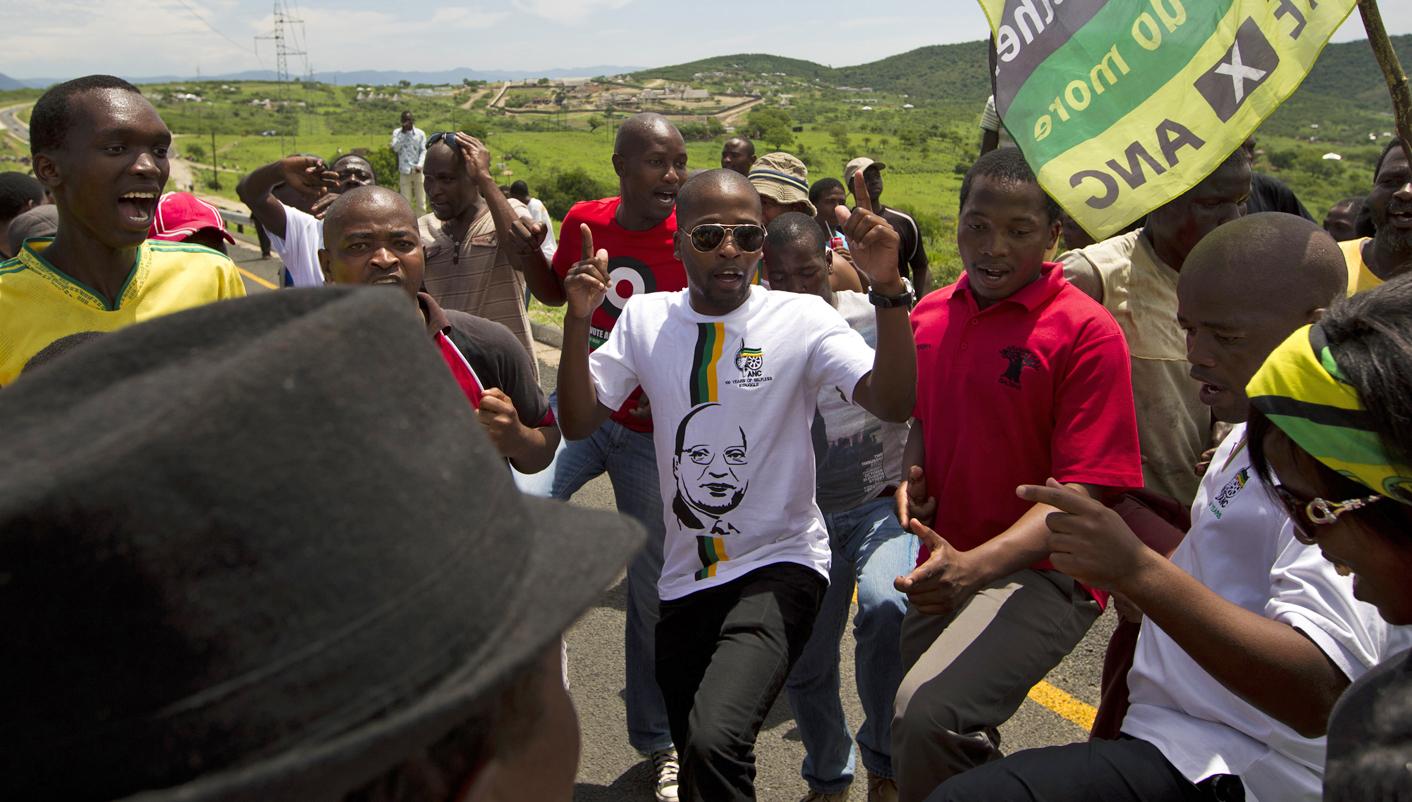 Supporters of South Africa's President Jacob Zuma block the road near his home as opposition party Democratic Alliance (DA) members walk toward them in Nkandla
