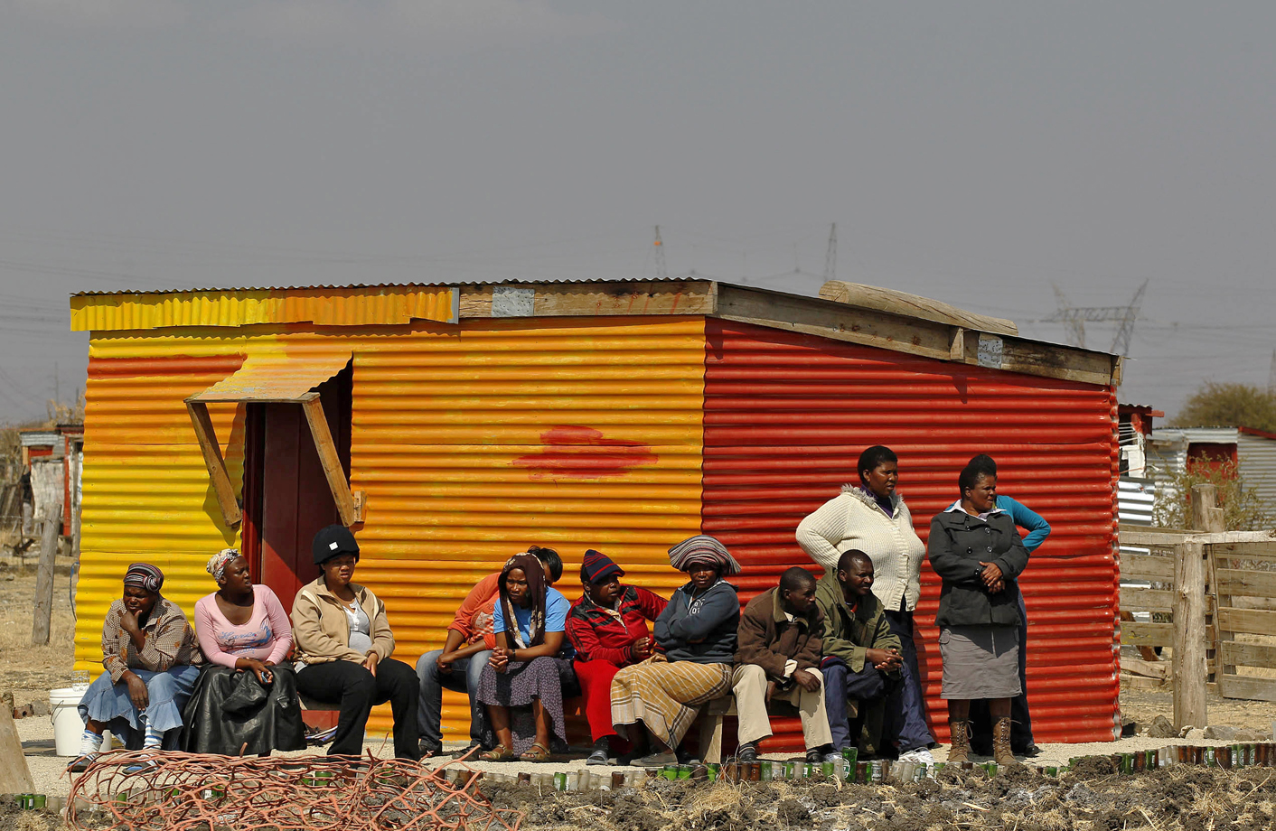 Women wait in front of a shack as they wait to be addressed by former African National Congress Youth League (ANCYL) President Julius Malema outside a South African mine in Rustenburg