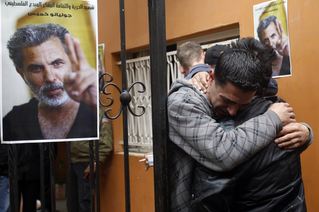 Palestinians mourn next to posters depicting Arab-Israeli actor and director Mer Khamis during a rally outside the Freedom Theatre in Jenin refugee camp