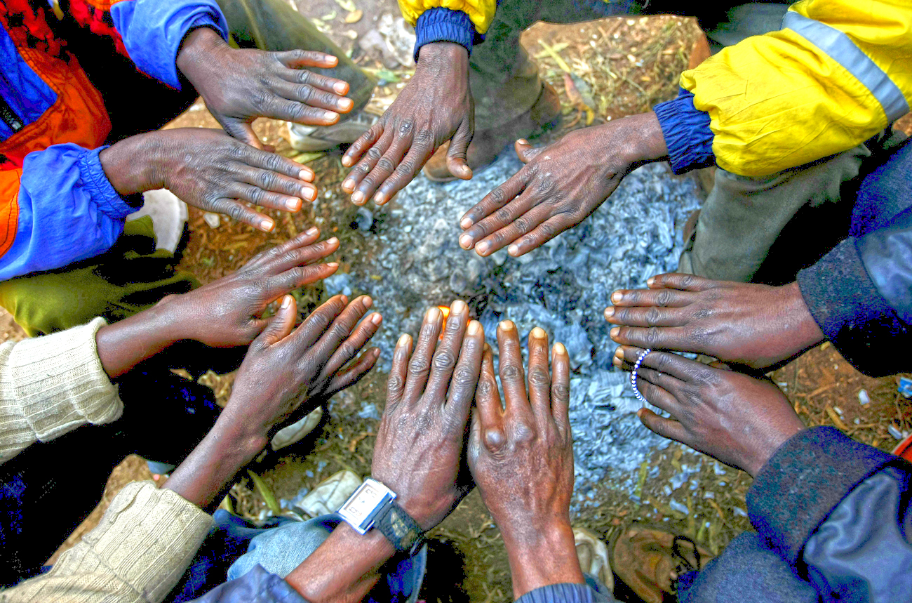 African immigrants, displaced by anti-foreigner violence in Johannesburg, warm their hands around a small fire outside the Jeppe police station in the city