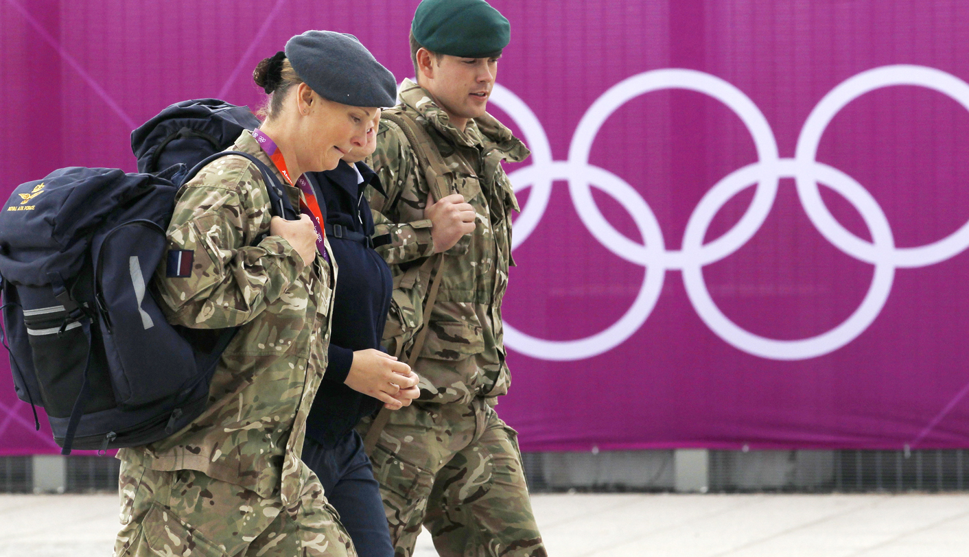 Members of the armed forces walk past the Olympic rings on the perimeter of the Olympic Park in Stratford, east London