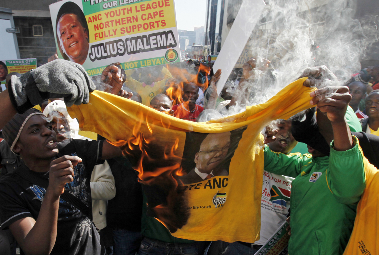 Supporters of ANC Youth League leader Julius Malema burn a shirt bearing the face of South Africa's President Jacob Zuma outside the party headquarters in central Johannesburg