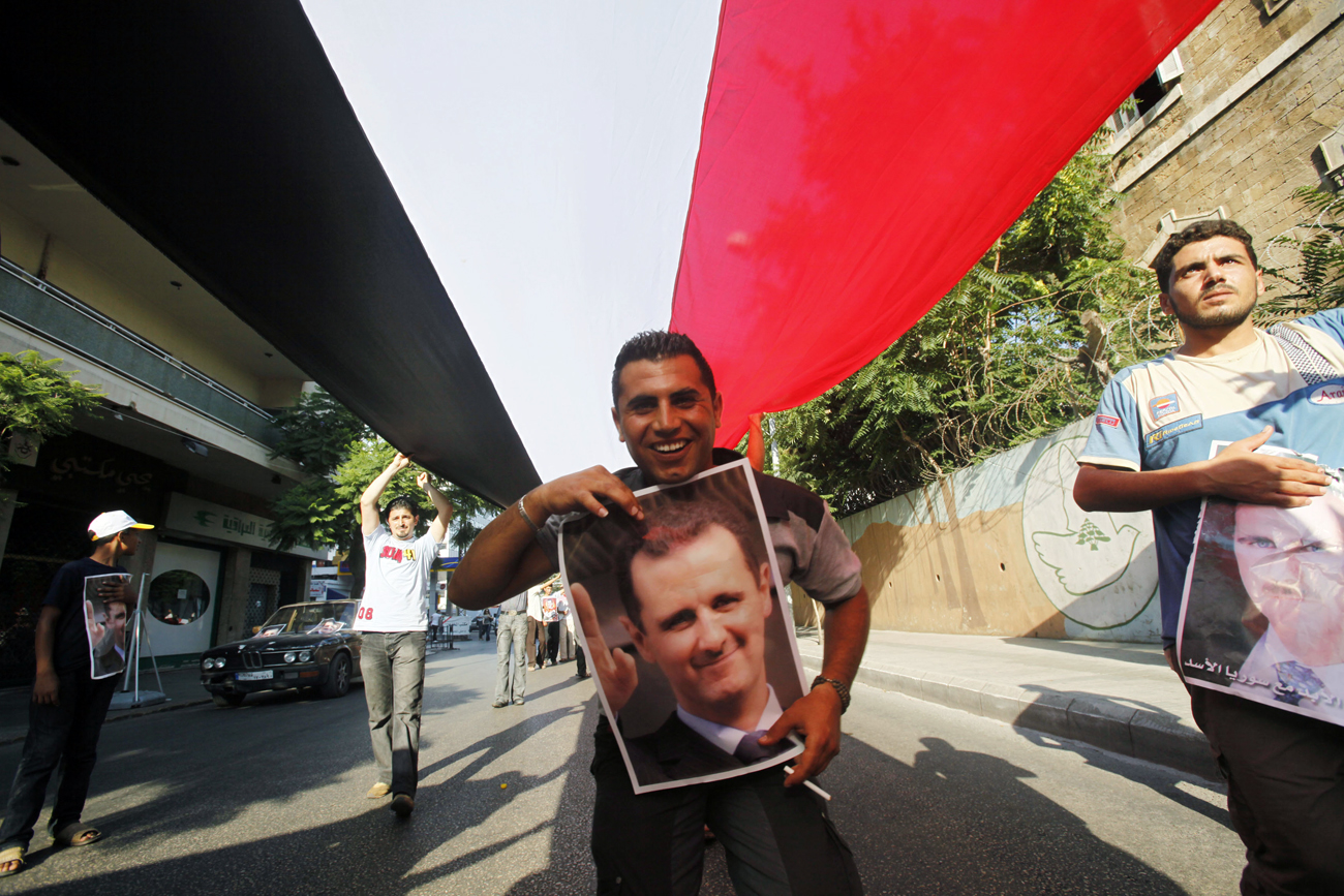 A Syrian living in Lebanon holds a poster of Syria's President Bashar al-Assad during a pro-government protest in Beirut