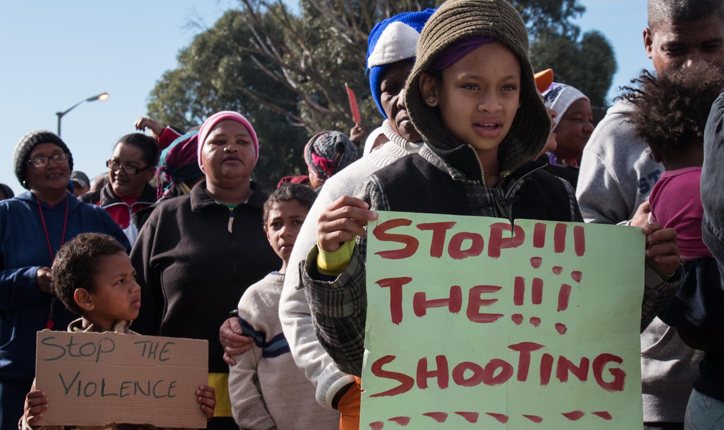 A young girl hold a sign reading: “Stop the shooting”
