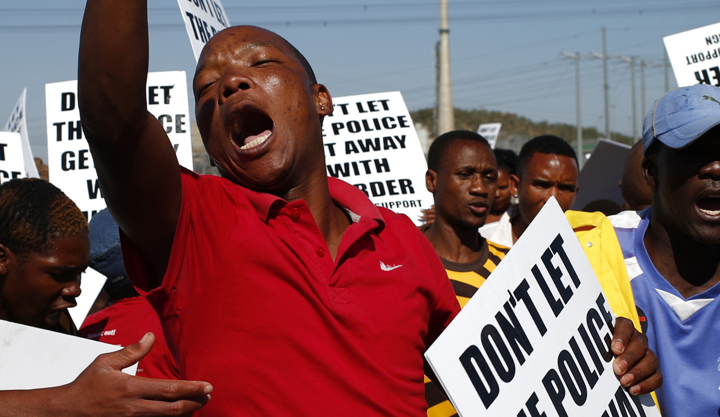 Demonstrators wave placards during a site inspection by the judicial commission of inquiry into the shootings at Lonmin's Marikana mine
