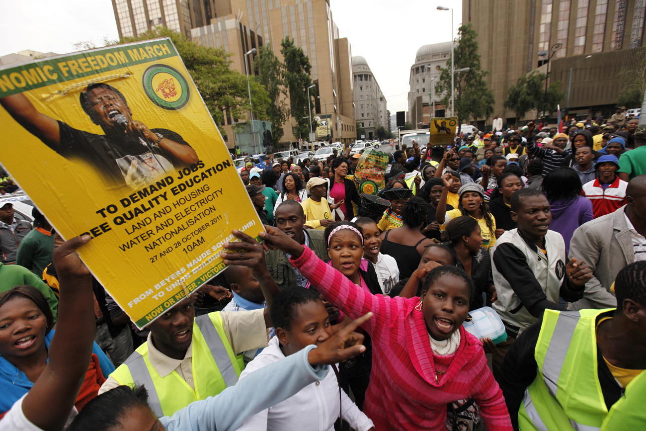 Supporters of the ANC Youth League President, Malema, carry a placard bearing his face as they chant before a march in central Johannesburg