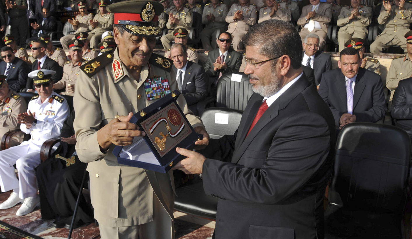 Egypt's new President Mursi receives a gift from Field Marshal Tantawi, head of Egypt's ruling SCAF, during a ceremony where the military handed over power to Mursi at a military base in Hikstep, east of Cairo
