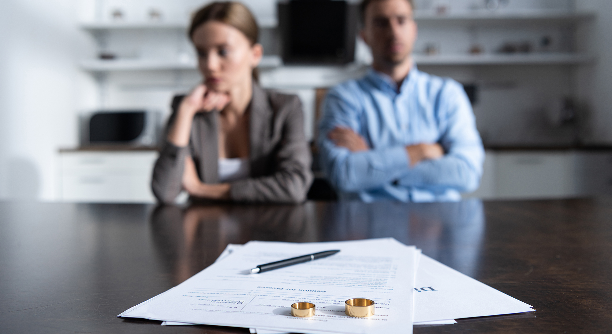 selective focus of couple sitting at table with divorce documents