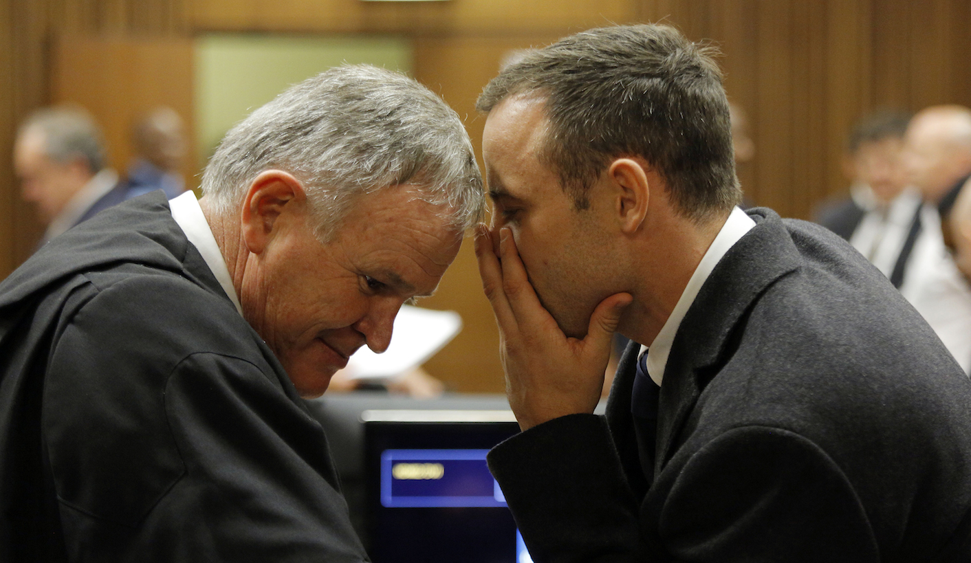 Oscar Pistorius speaks to his defence lawyer Barry Roux during the second day of the trial of the Olympic and Paralympic track star at the North Gauteng High Court in Pretoria