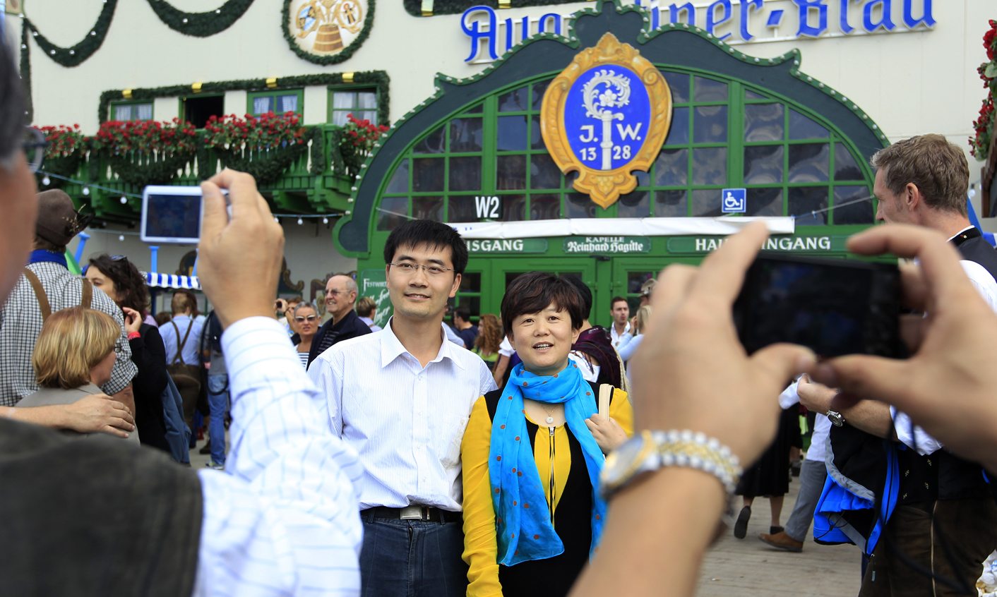 Chinese tourists pose in front of tent during visit at Oktoberfest in Munich