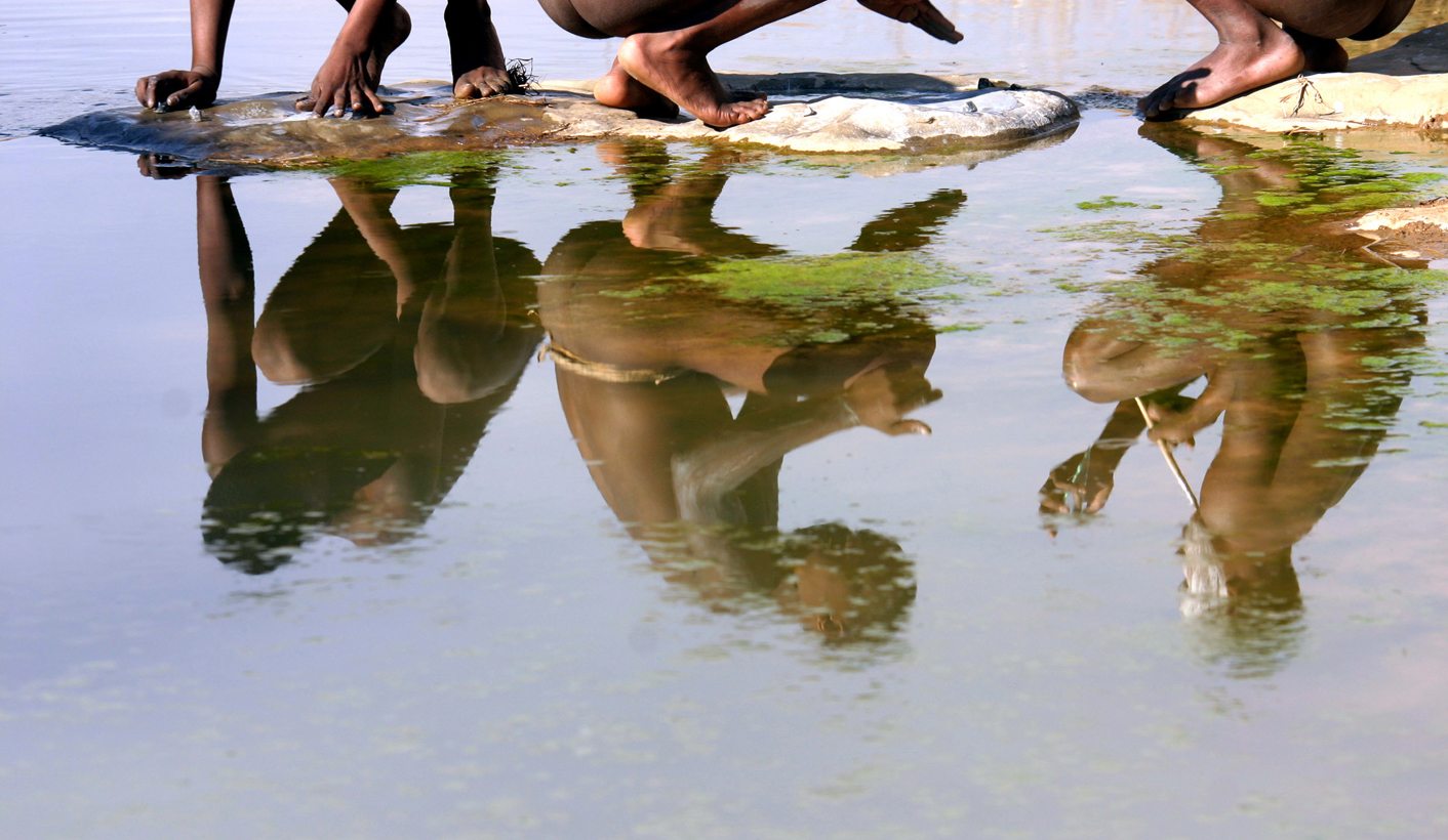 Initiates are reflected in the water as they wash off ikota (white lime stone) in the Eastern Cape, South Africa