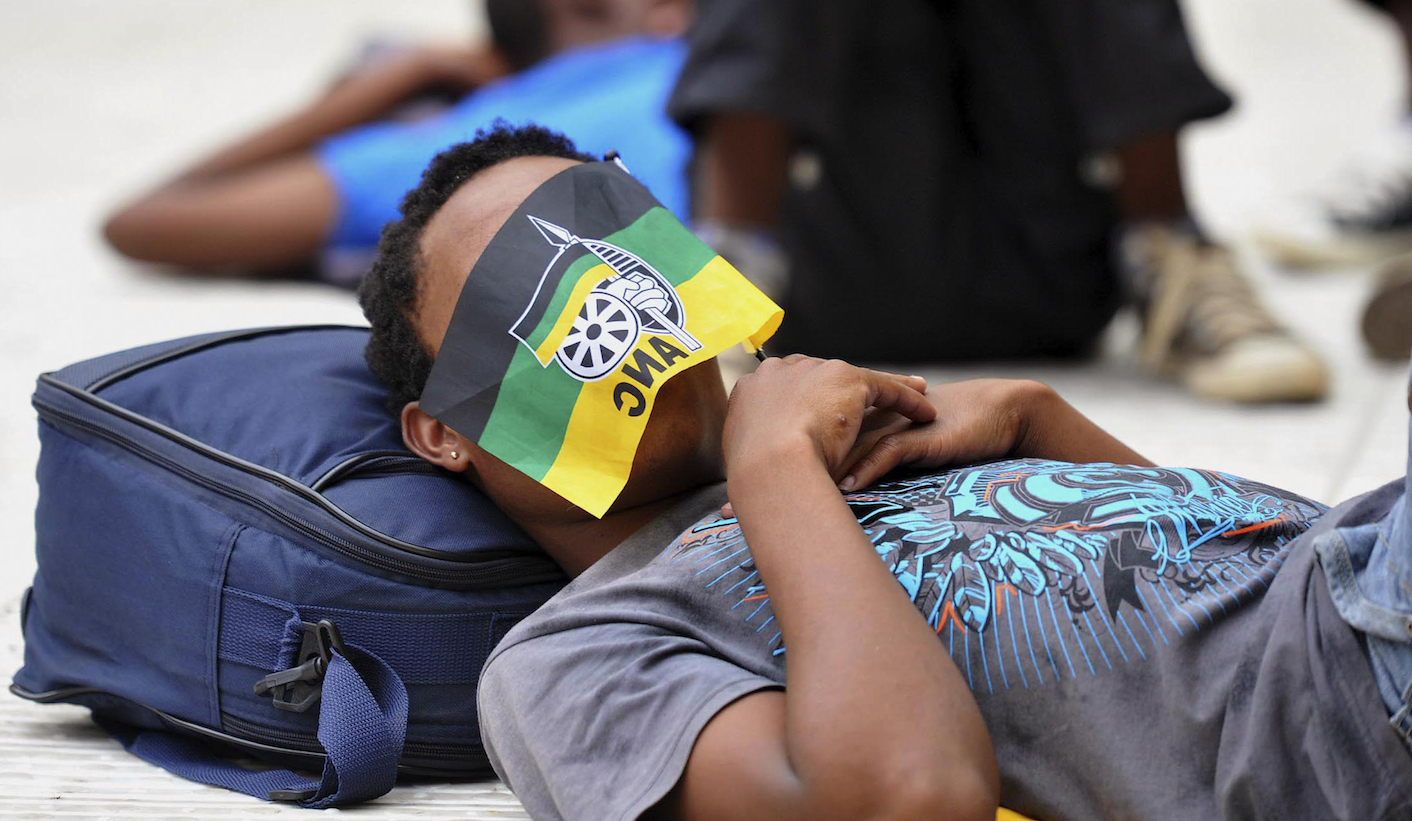 A supporter of  the ruling ANC party uses a miniature party's flag to block his face from the sun as he naps during the party's 102nd anniversary celebration in Nelspruit
