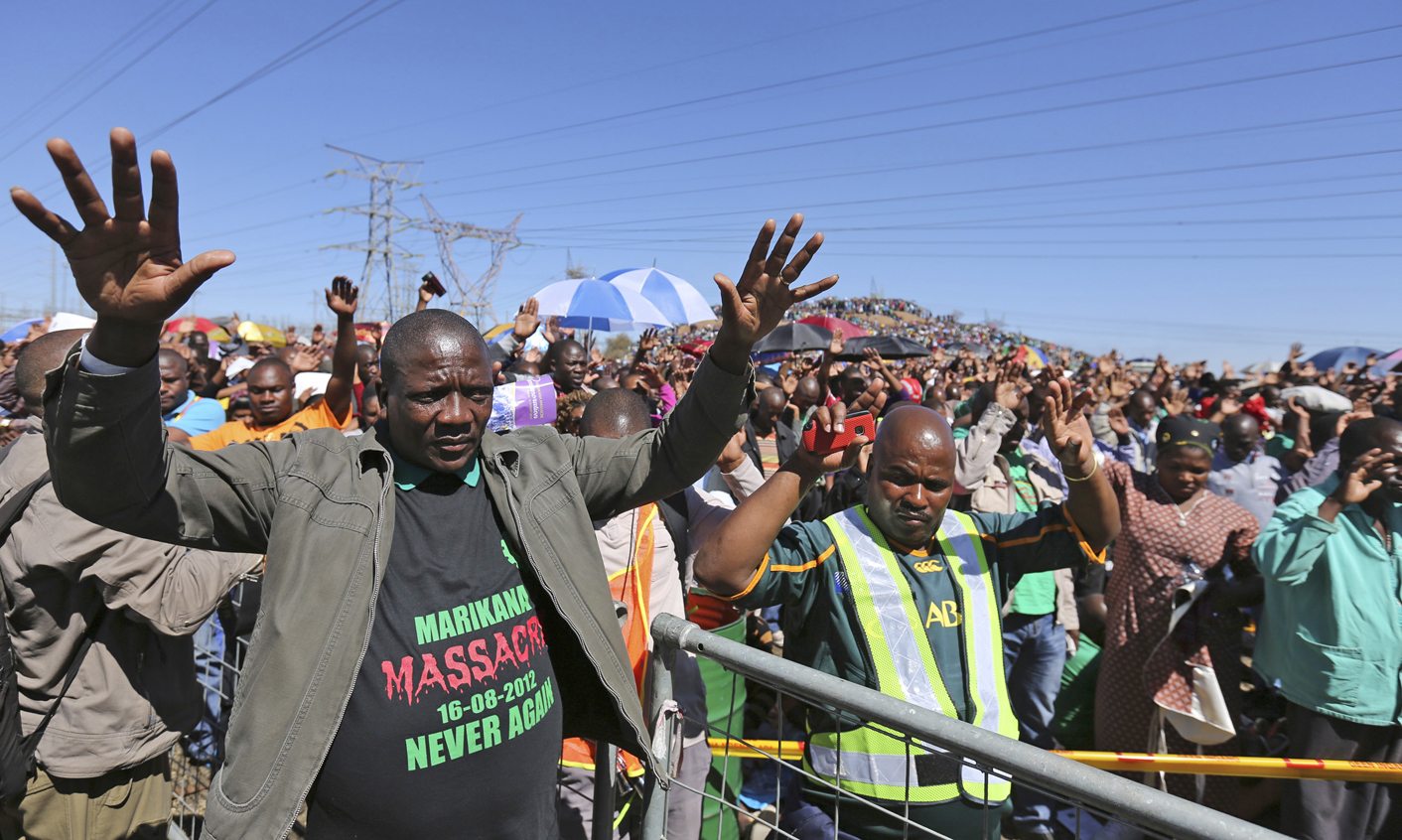 Miners gesture as they pray outside the Lonmin's Marikana platinum mine in Rustenburg