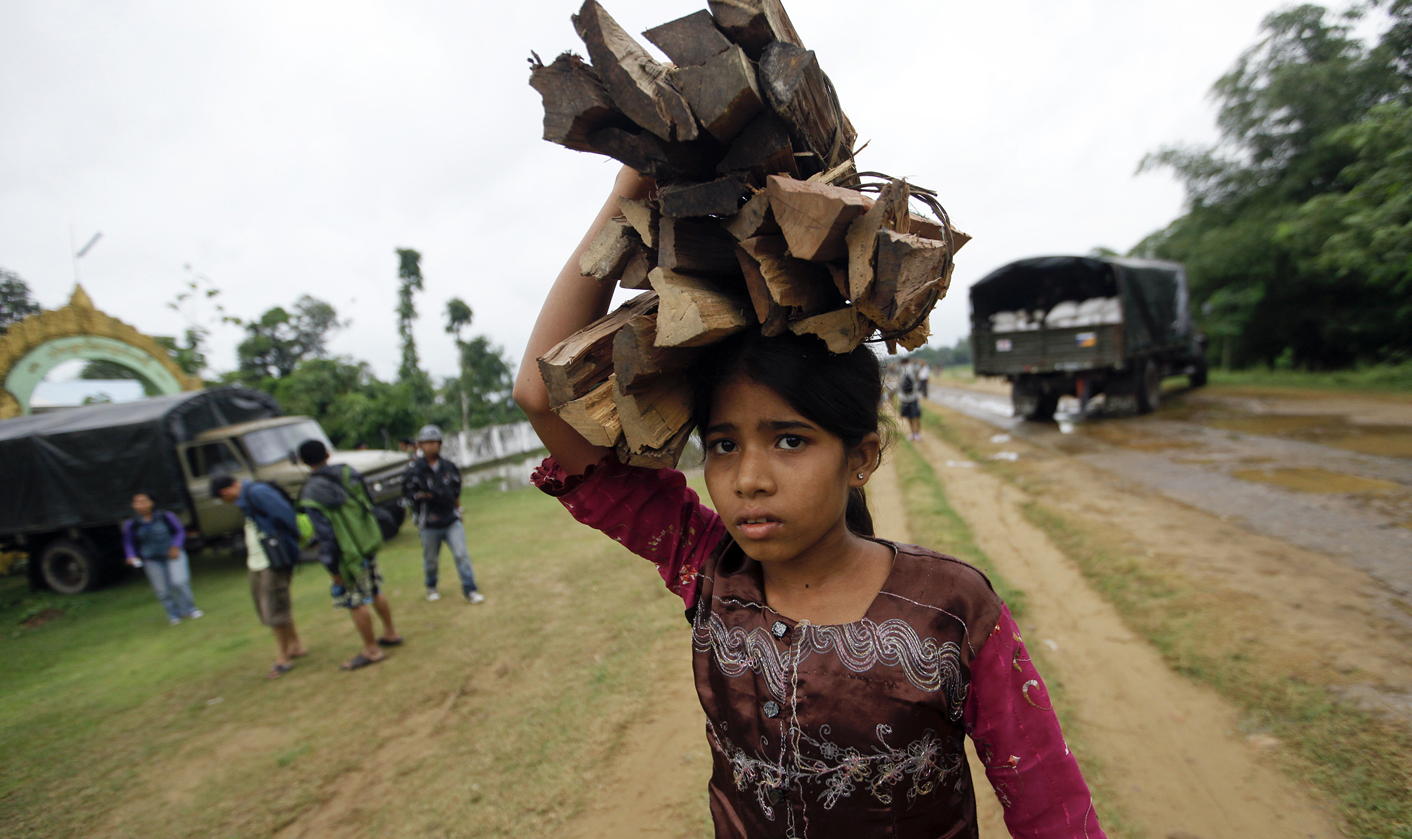 A Rohingya girl carries firewood at a camp for those displaced by recent violence, outside Sittwe